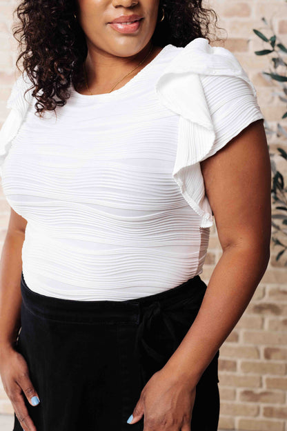 Detailed view of textured white jersey knit and layered flutter sleeve construction on Ila Blouse.