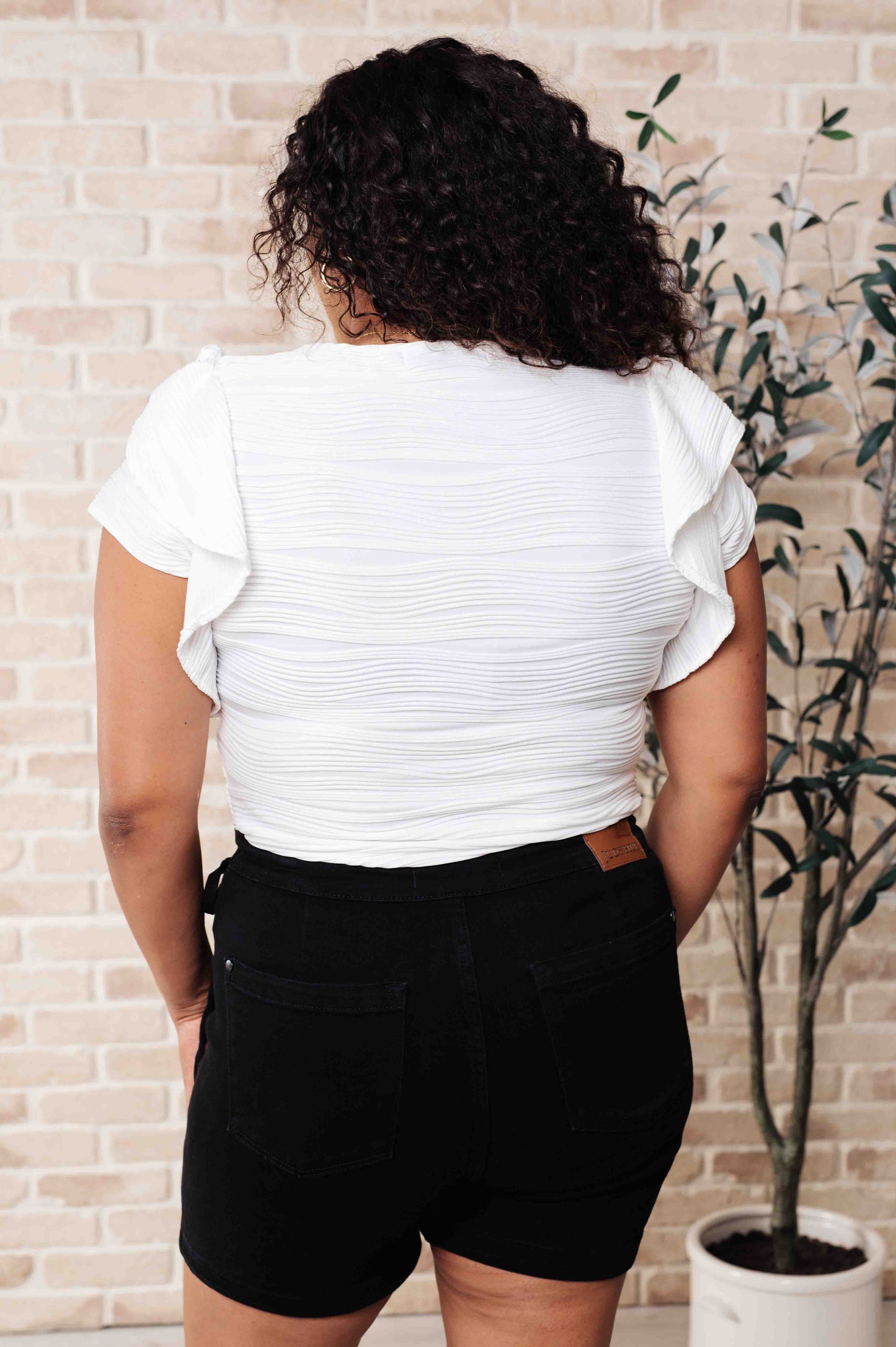 Plus-size back view of Ila Blouse in white with flutter sleeve details and textured knit finish.