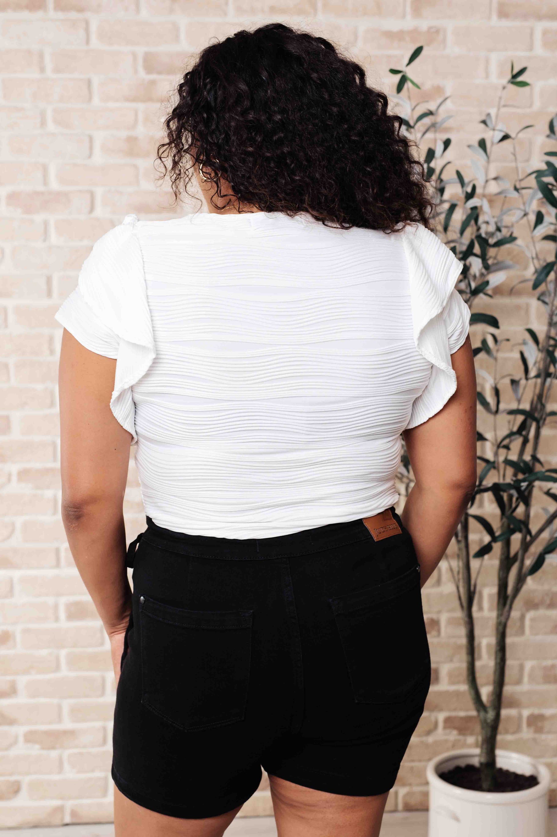 Plus-size back view of Ila Blouse in white with flutter sleeve details and textured knit finish.