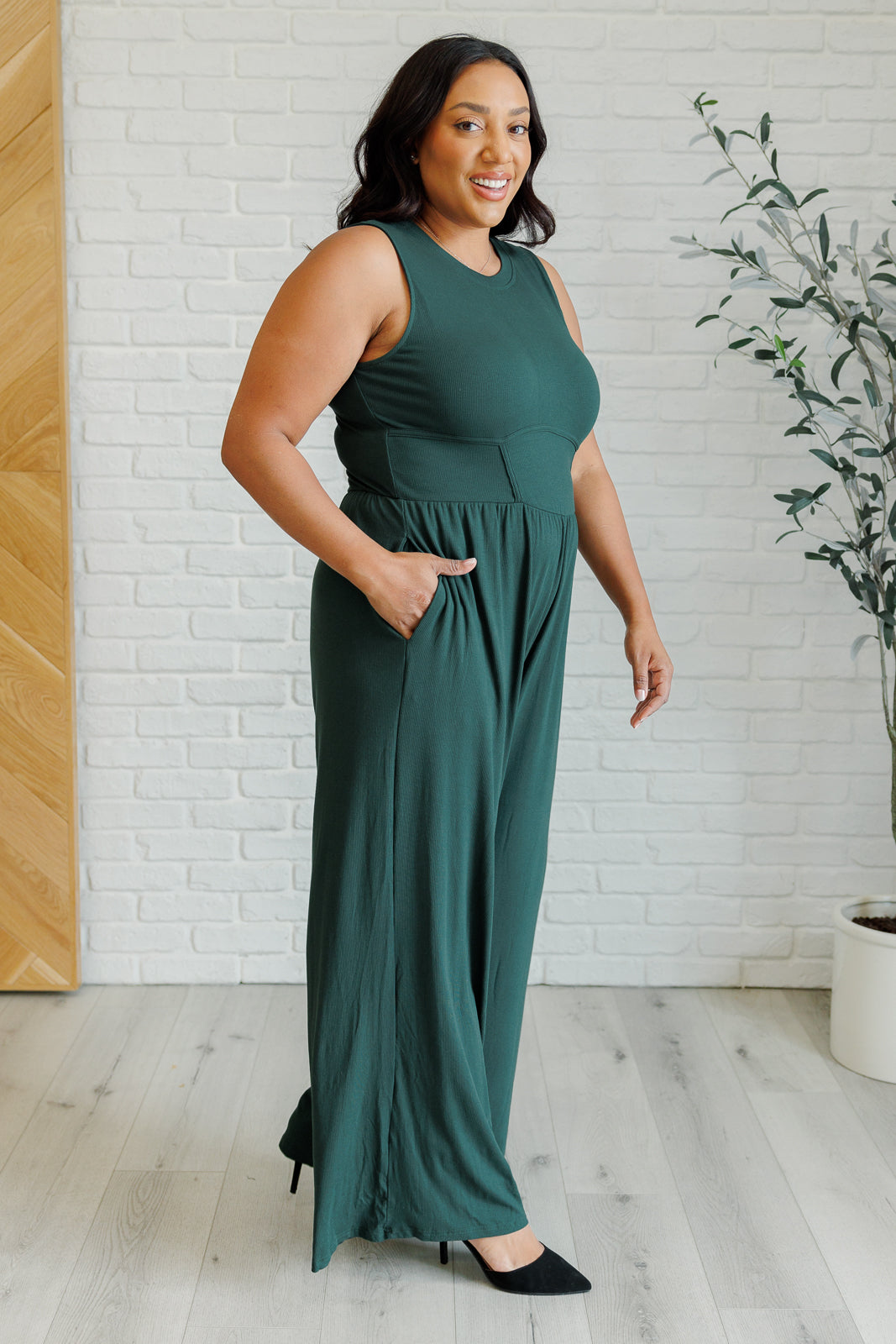 Green ribbed wide-leg jumpsuit with round neckline, sleeveless design, flattering stretchy waistline, hidden zipper closure, and pockets. Offers full bra coverage with wide straps.