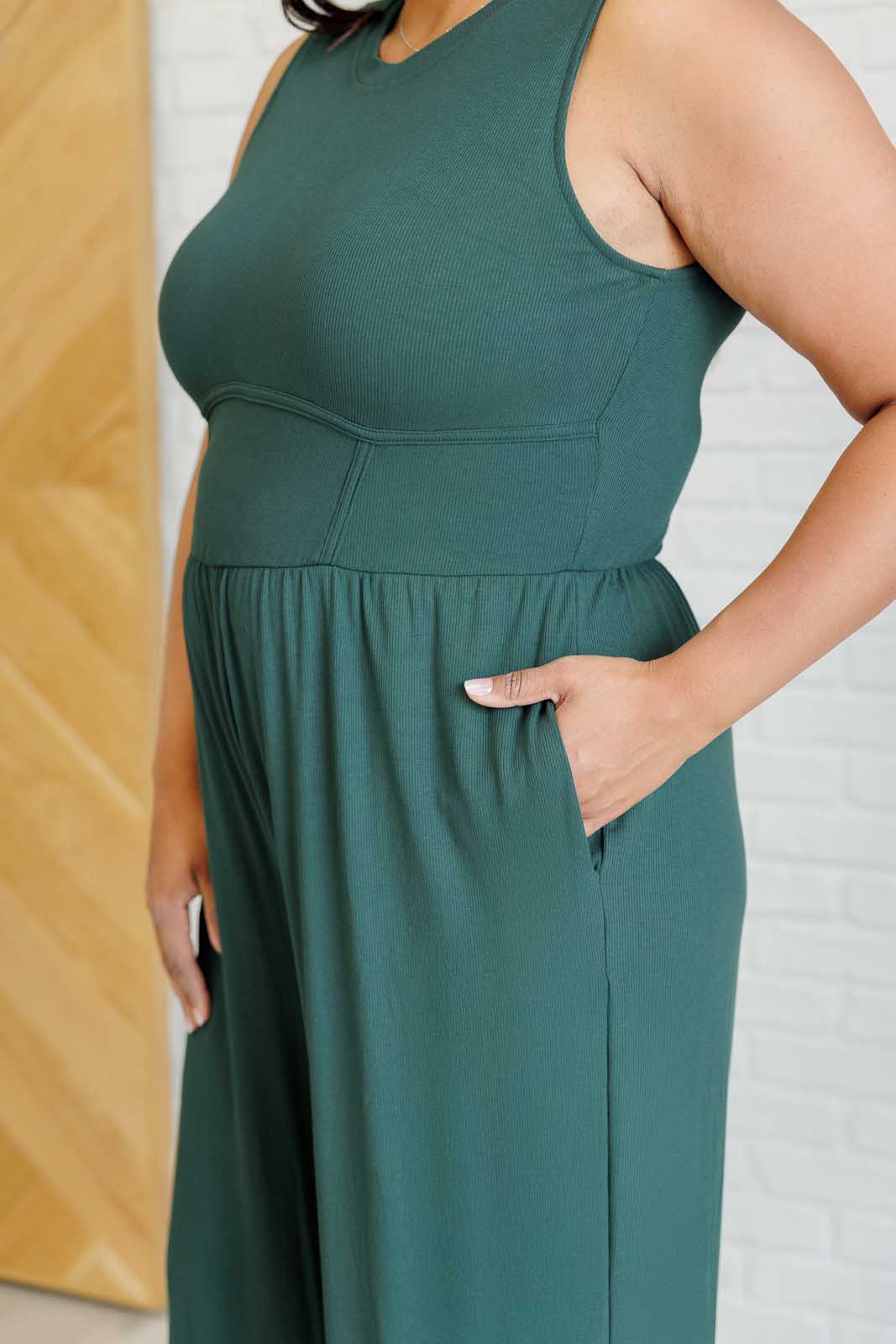 Green ribbed wide-leg jumpsuit with round neckline, sleeveless design, flattering stretchy waistline, hidden zipper closure, and pockets. Offers full bra coverage with wide straps.