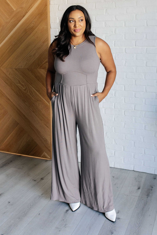 Gray ribbed sleeveless wide-leg jumpsuit with a round neckline, stretchy waistline, and hidden zipper closure. Features wide straps for full bra coverage and functional pockets.