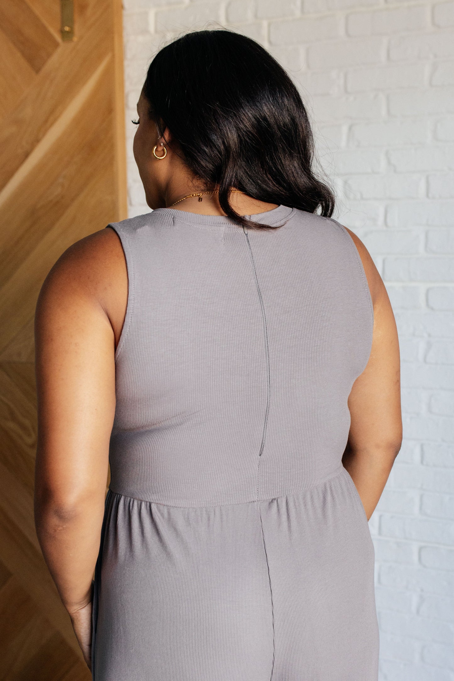 Gray ribbed sleeveless wide-leg jumpsuit with a round neckline, stretchy waistline, and hidden zipper closure. Features wide straps for full bra coverage and functional pockets.