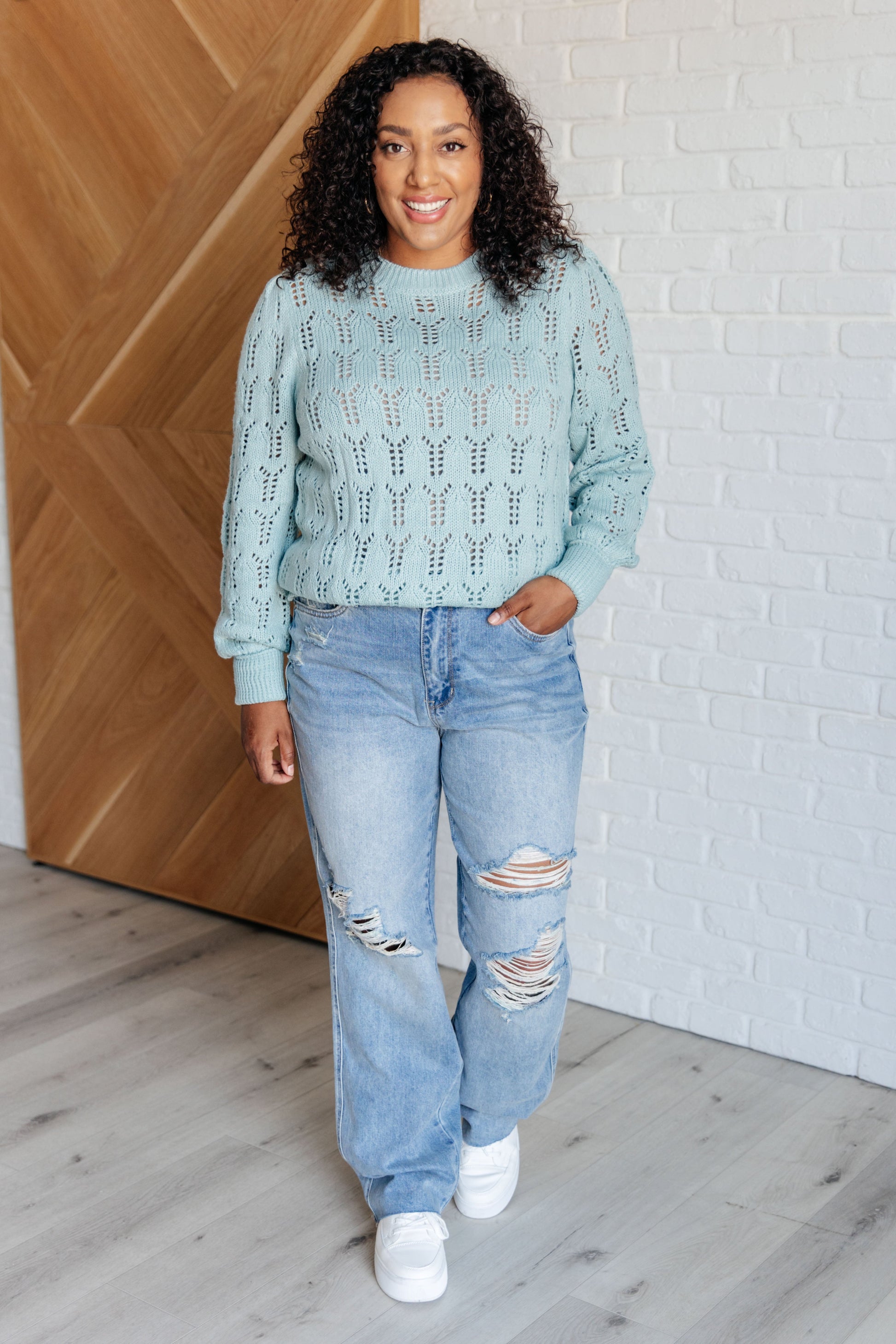 Light blue pointelle knit sweater with a round neckline, long cuffed sleeves, and sheer, lightweight fabric.