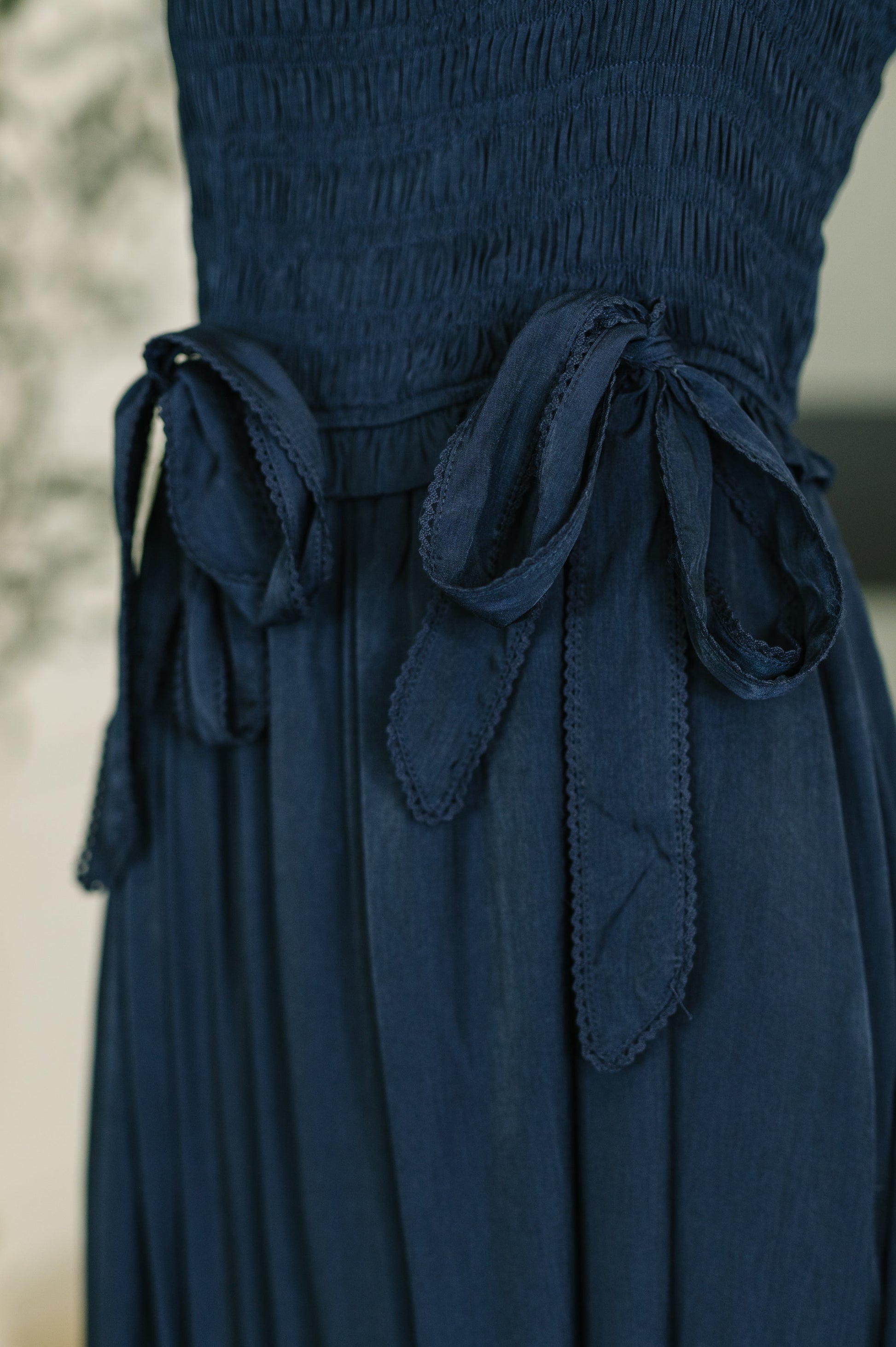 Close up of Holland Midi Dress in Navy functional bow tie neckline detail.