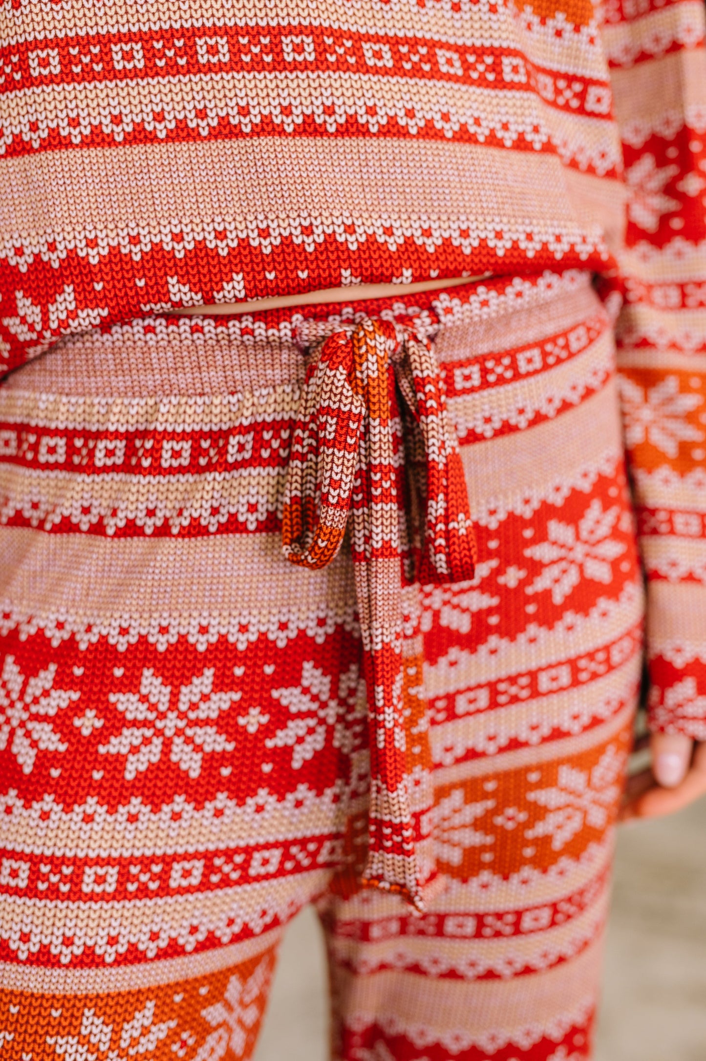 Fabric close-up of Holly's Jolly Pajama Set showing red holiday print knit.