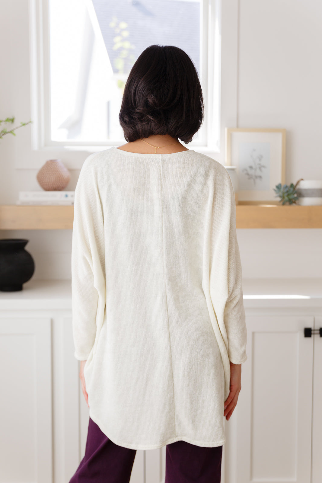 Women's off-white cardigan made from lightweight sweater knit fabric. Features an open front, long dolman sleeves, and a scooped hem.