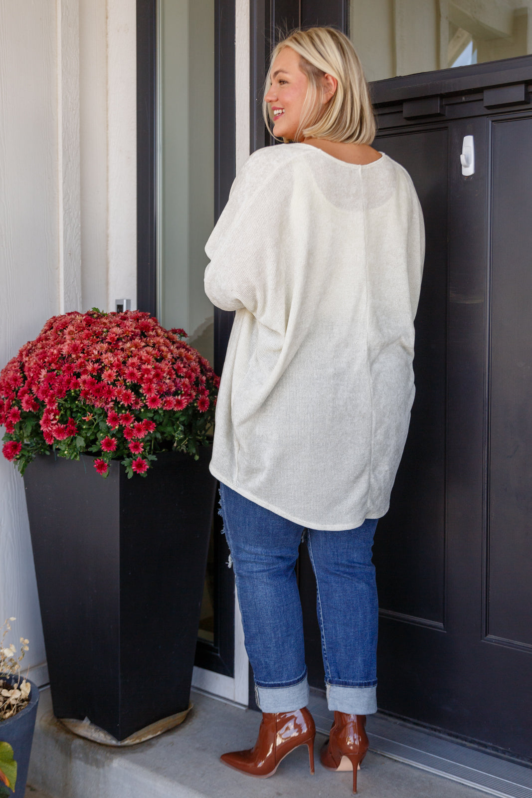 Women's off-white cardigan made from lightweight sweater knit fabric. Features an open front, long dolman sleeves, and a scooped hem.