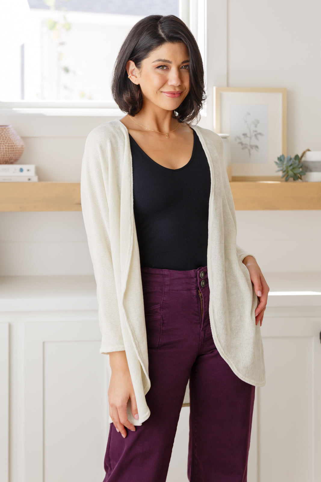 Women's off-white cardigan made from lightweight sweater knit fabric. Features an open front, long dolman sleeves, and a scooped hem.