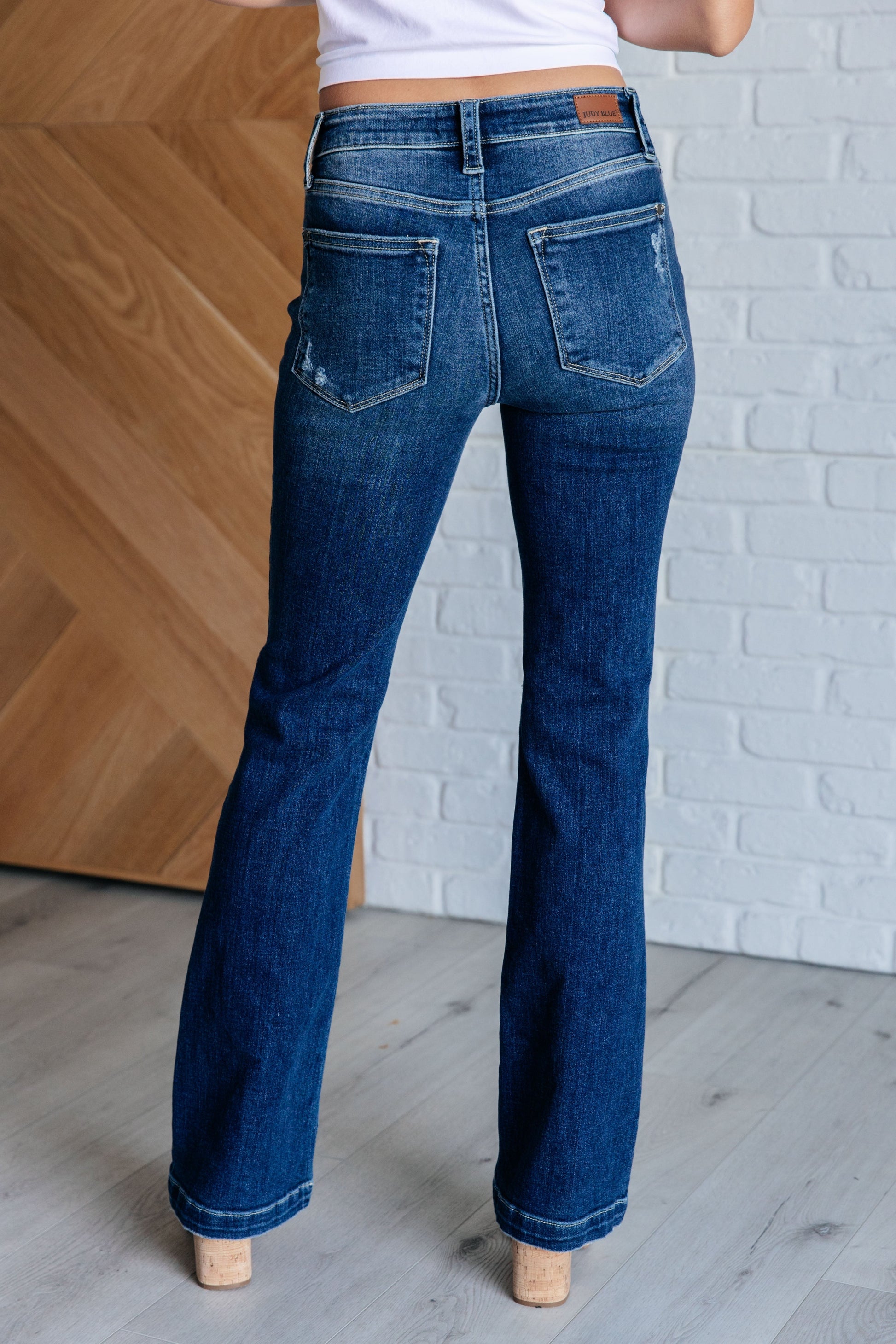 Judy Blue mid-rise distressed bootcut jeans in a dark wash, featuring a zip fly, 4-way stretch, and a stylish bootcut silhouette.