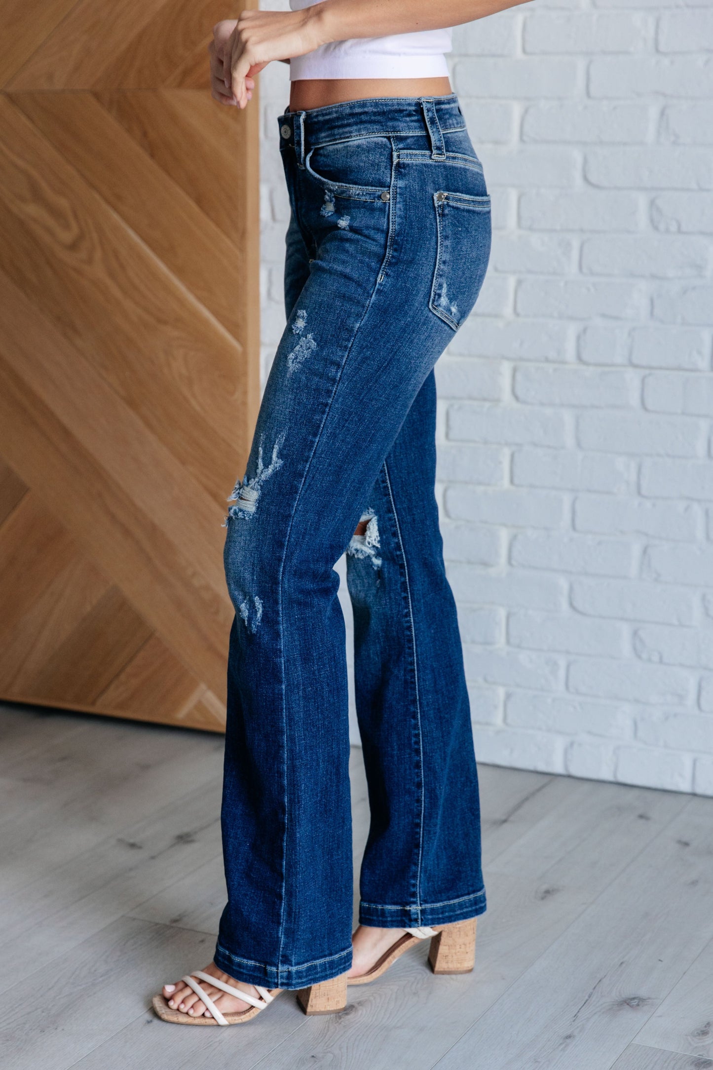 Judy Blue mid-rise distressed bootcut jeans in a dark wash, featuring a zip fly, 4-way stretch, and a stylish bootcut silhouette.