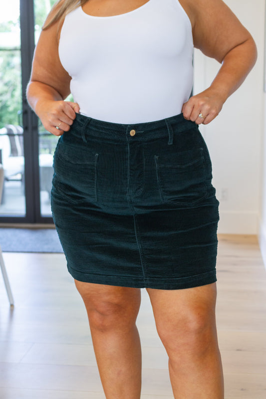 Emerald corduroy high-rise mini skirt with patch pockets, button closure, and zip fly. Casual style.