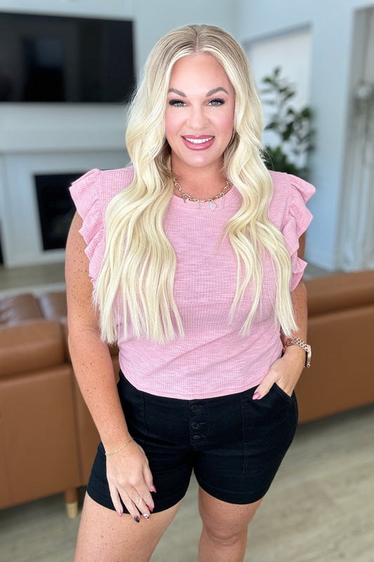 Plus-size model wearing pink ribbed cropped top with ruffle sleeves and round neckline.