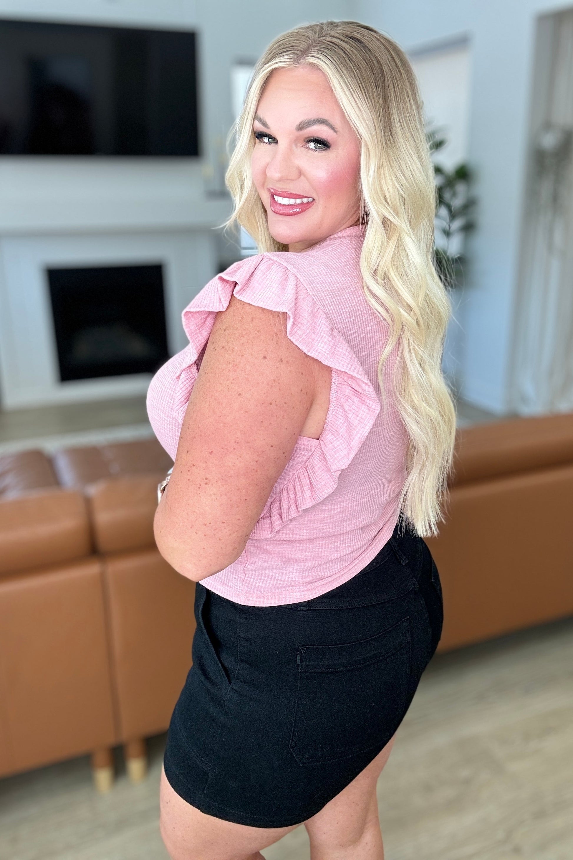 Plus-size model in pink cropped ribbed top with ruffle sleeves and side profile fit.
