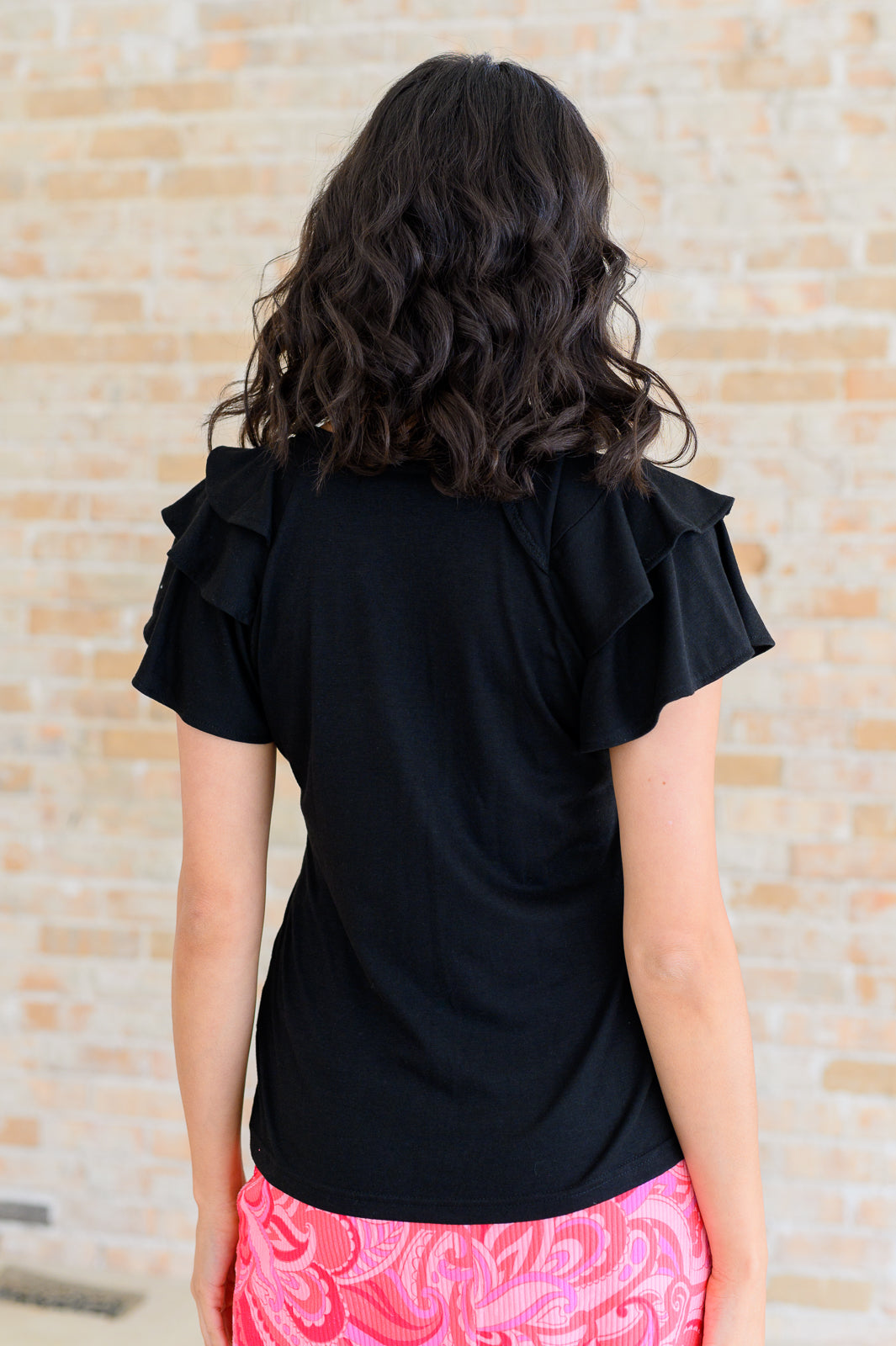 Solana Flutter Sleeve Tee in black ribbed jersey knit back view with layered flutter sleeves.
