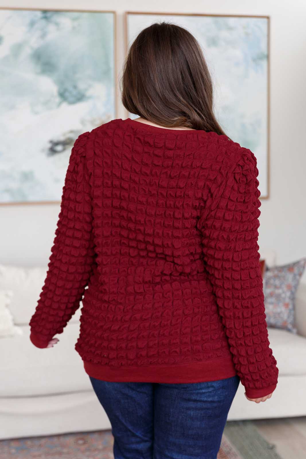 Wine-colored pullover with a crew neckline, long puff sleeves, slight shoulder padding, and ribbed cuffs and hem. Made from bubble-textured knit fabric.