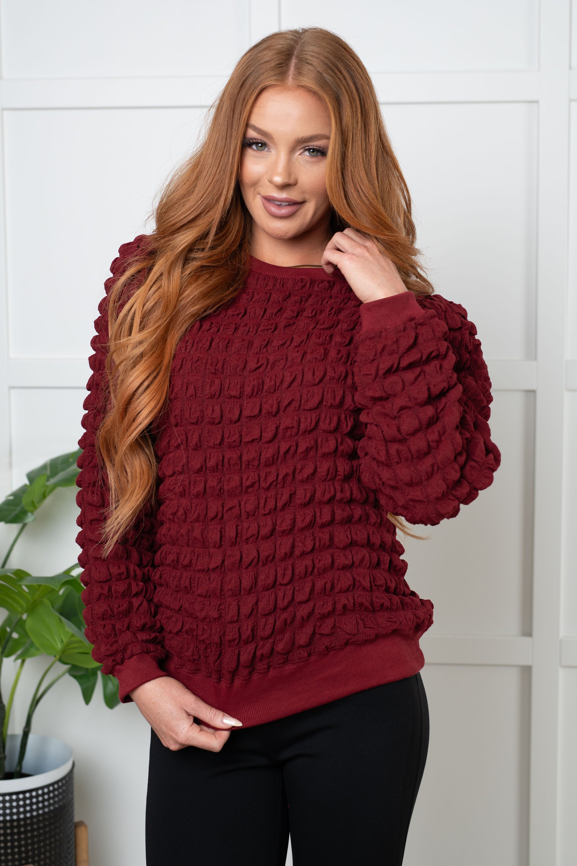 Wine-colored pullover with a crew neckline, long puff sleeves, slight shoulder padding, and ribbed cuffs and hem. Made from bubble-textured knit fabric.