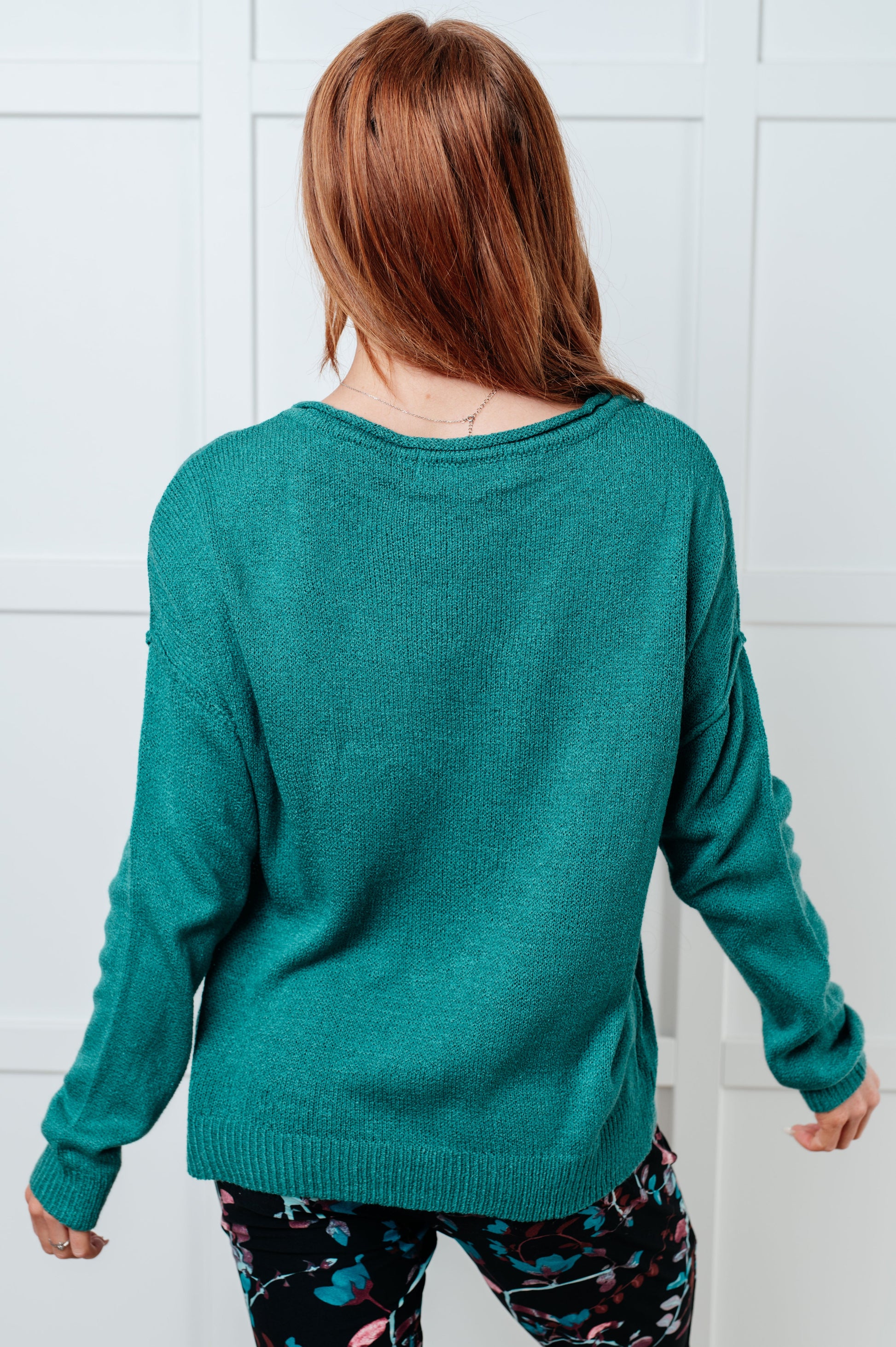 Teal women's sweater featuring a ribbed exposed seam boat neckline, long drop-shoulder sleeves, exposed seam, ribbed cuffs and hemline, and a chest pocket.