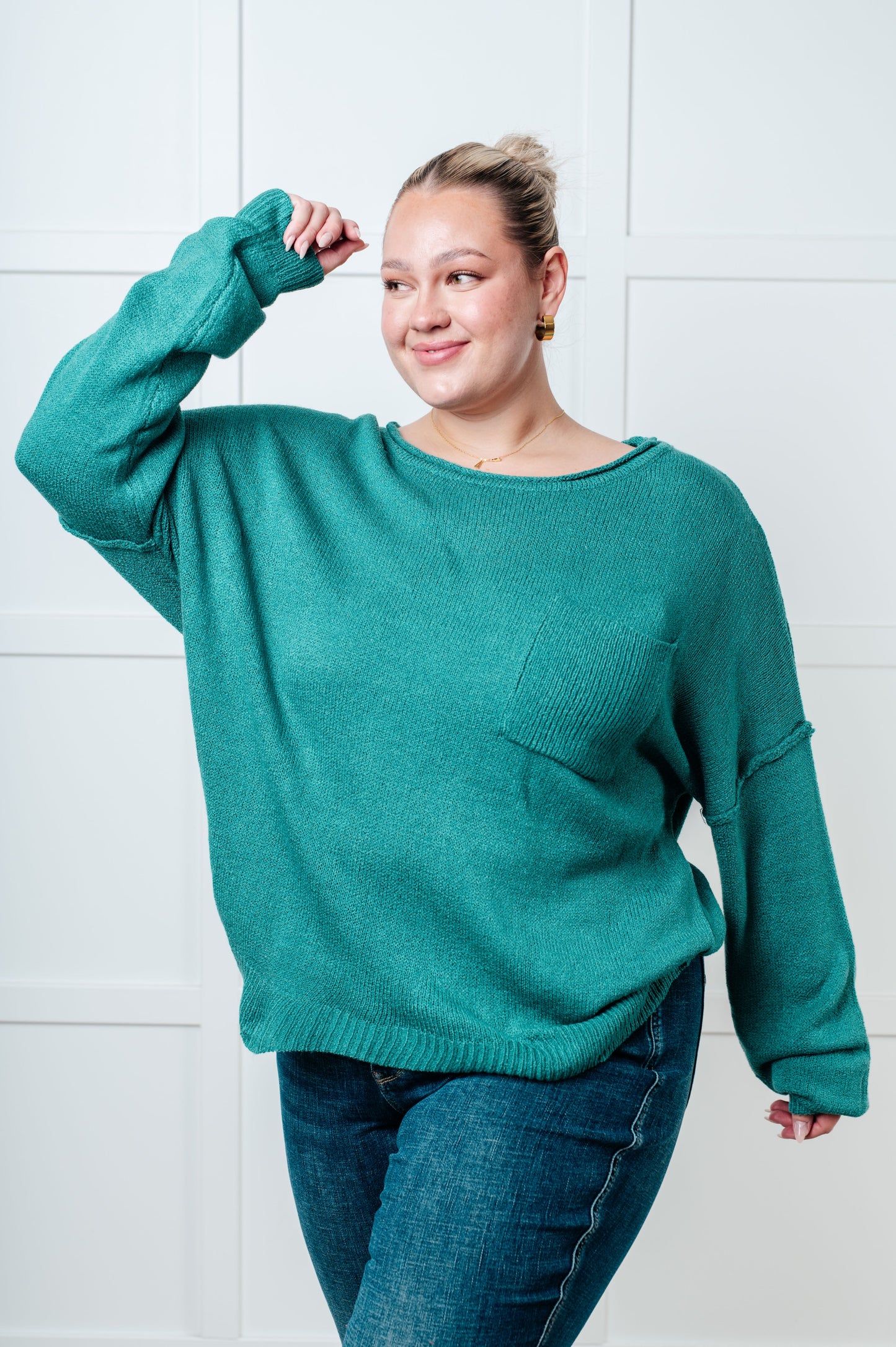 Teal women's sweater featuring a ribbed exposed seam boat neckline, long drop-shoulder sleeves, exposed seam, ribbed cuffs and hemline, and a chest pocket.