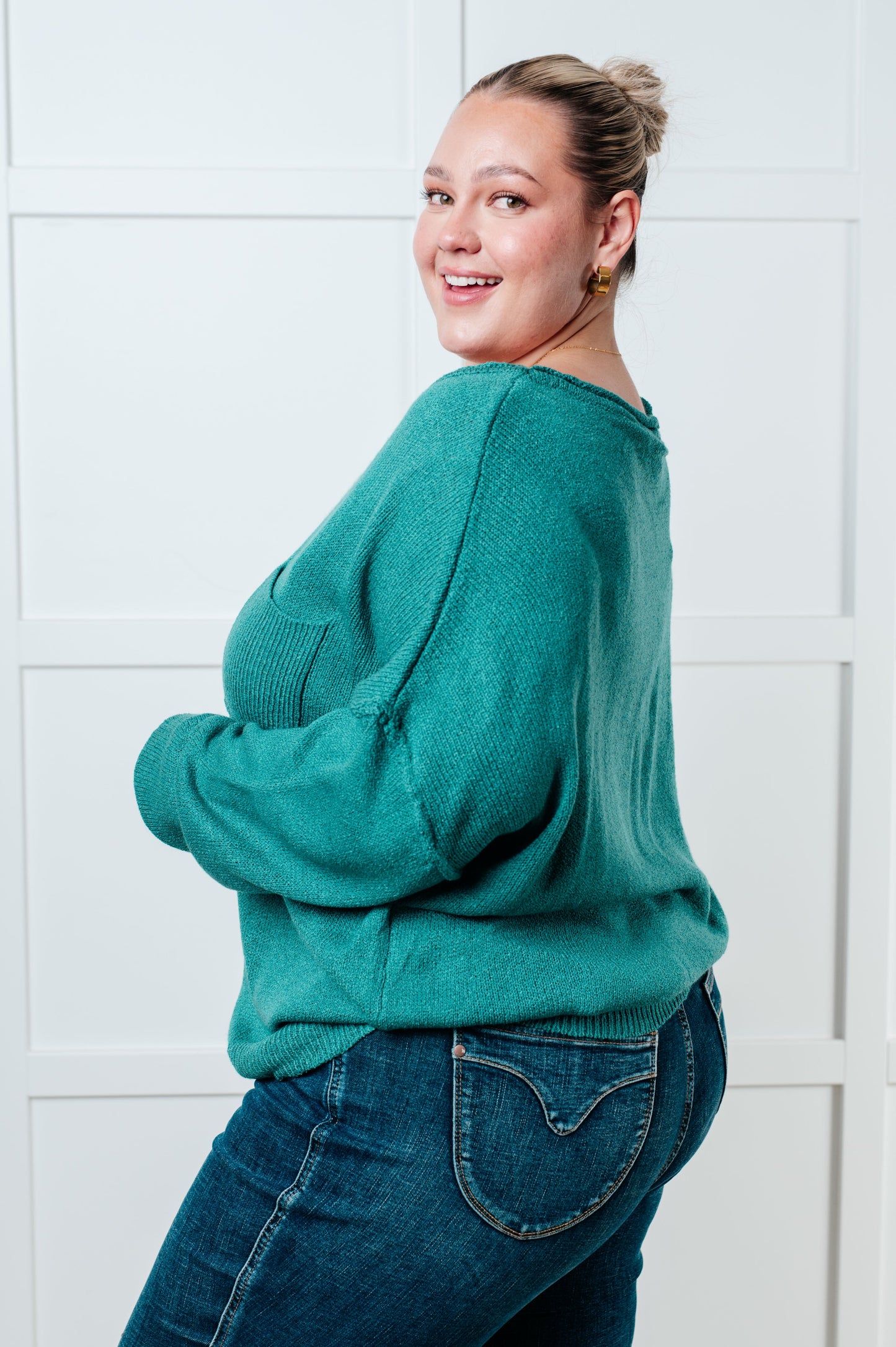 Teal women's sweater featuring a ribbed exposed seam boat neckline, long drop-shoulder sleeves, exposed seam, ribbed cuffs and hemline, and a chest pocket.