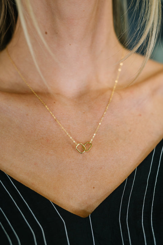 Woman wearing In This Together Necklace with interlocking gold-plated rings and zirconia diamond accents.