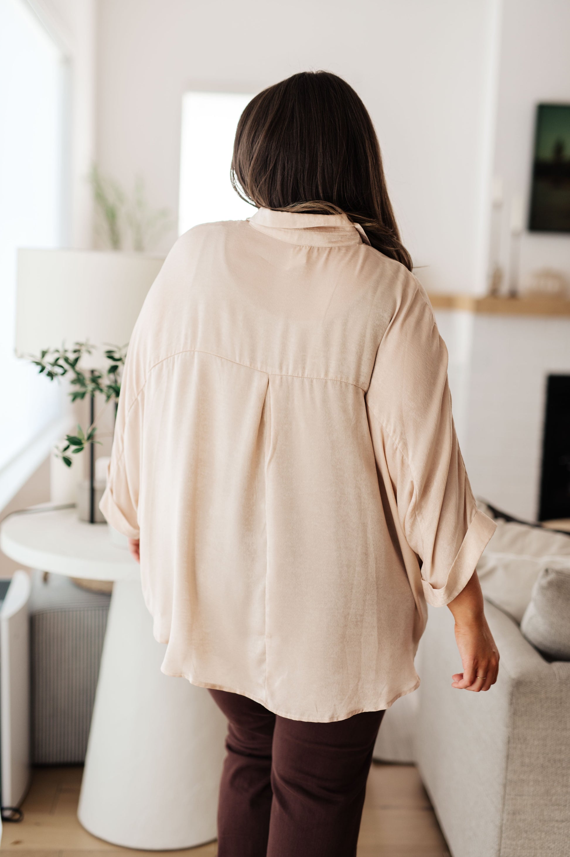 Champagne-colored poly satin top with a collared neckline, quarter-length button placket, oversized dolman sleeves with rolled cuffs, and a boxy, oversized fit.