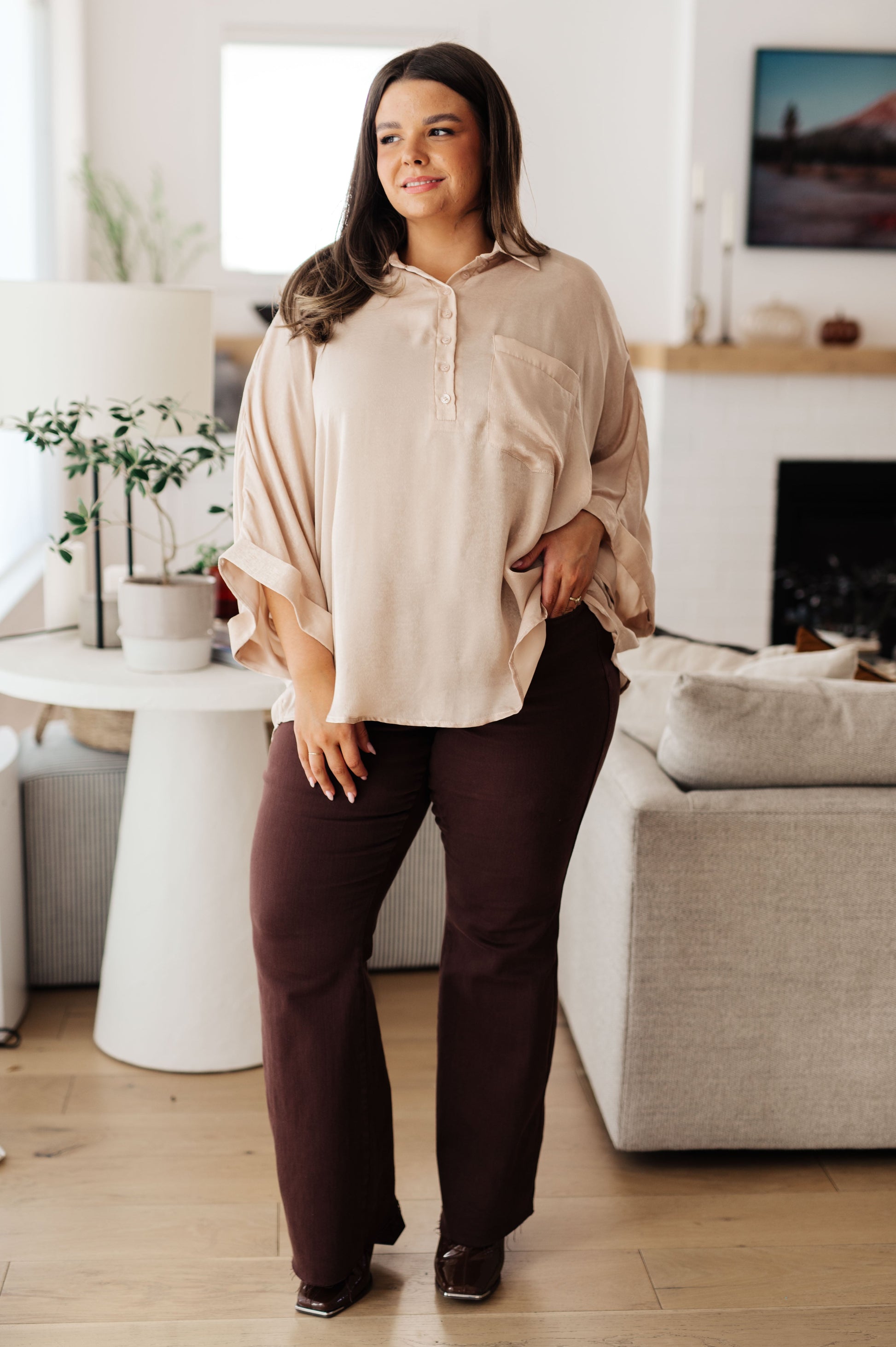 Champagne-colored poly satin top with a collared neckline, quarter-length button placket, oversized dolman sleeves with rolled cuffs, and a boxy, oversized fit.