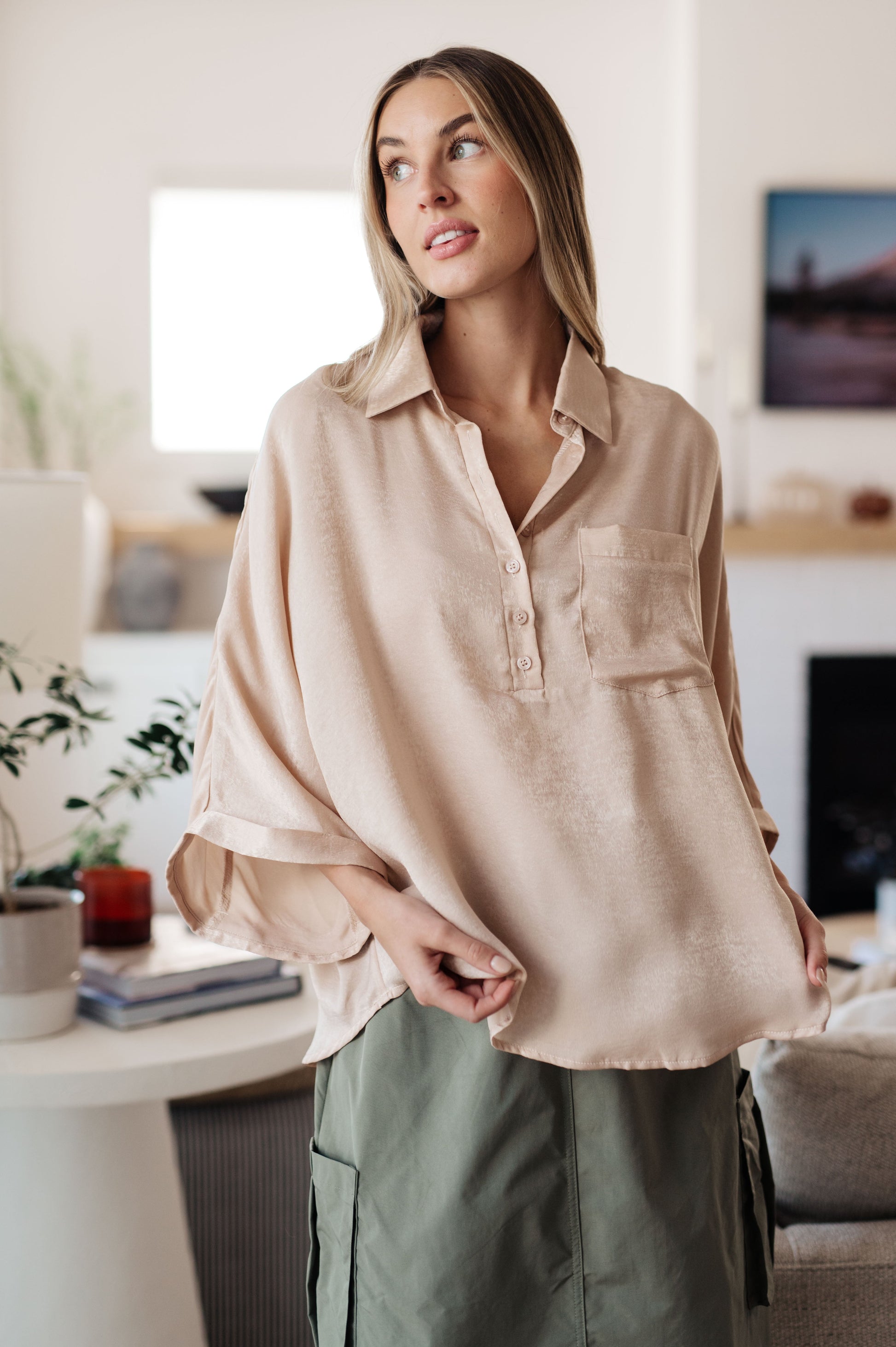 Champagne-colored poly satin top with a collared neckline, quarter-length button placket, oversized dolman sleeves with rolled cuffs, and a boxy, oversized fit.