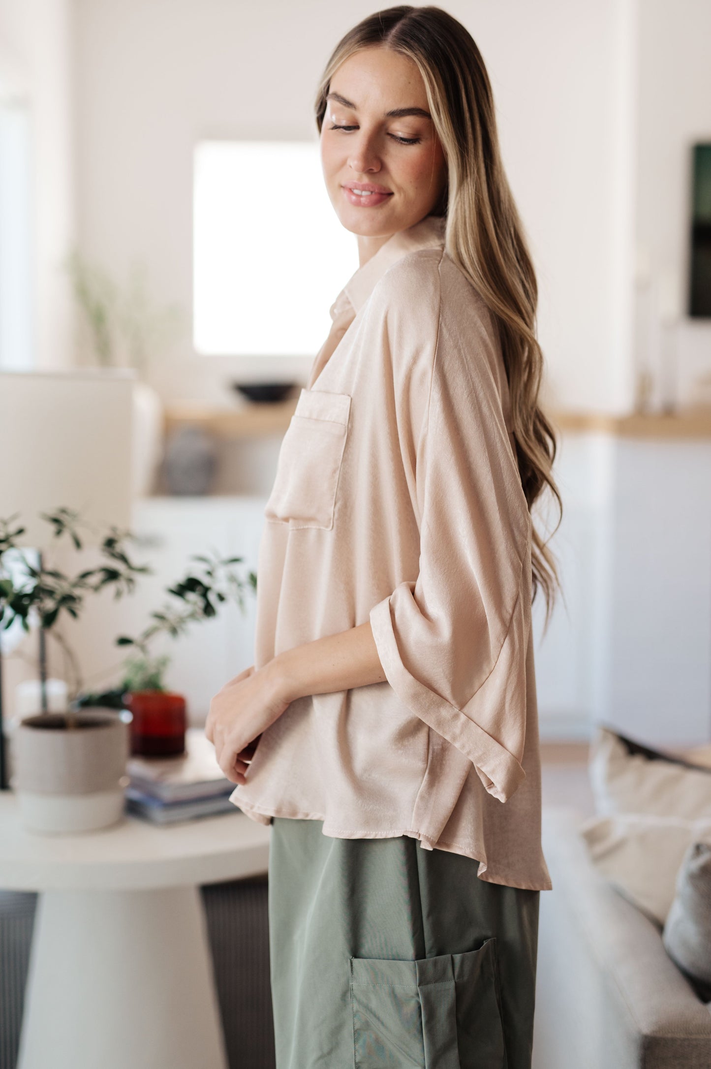 Champagne-colored poly satin top with a collared neckline, quarter-length button placket, oversized dolman sleeves with rolled cuffs, and a boxy, oversized fit.