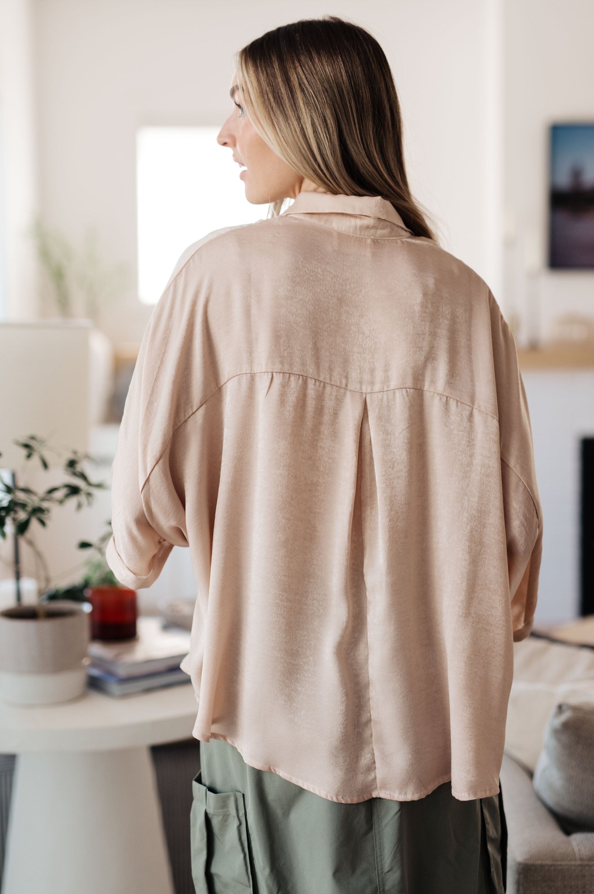 Champagne-colored poly satin top with a collared neckline, quarter-length button placket, oversized dolman sleeves with rolled cuffs, and a boxy, oversized fit.