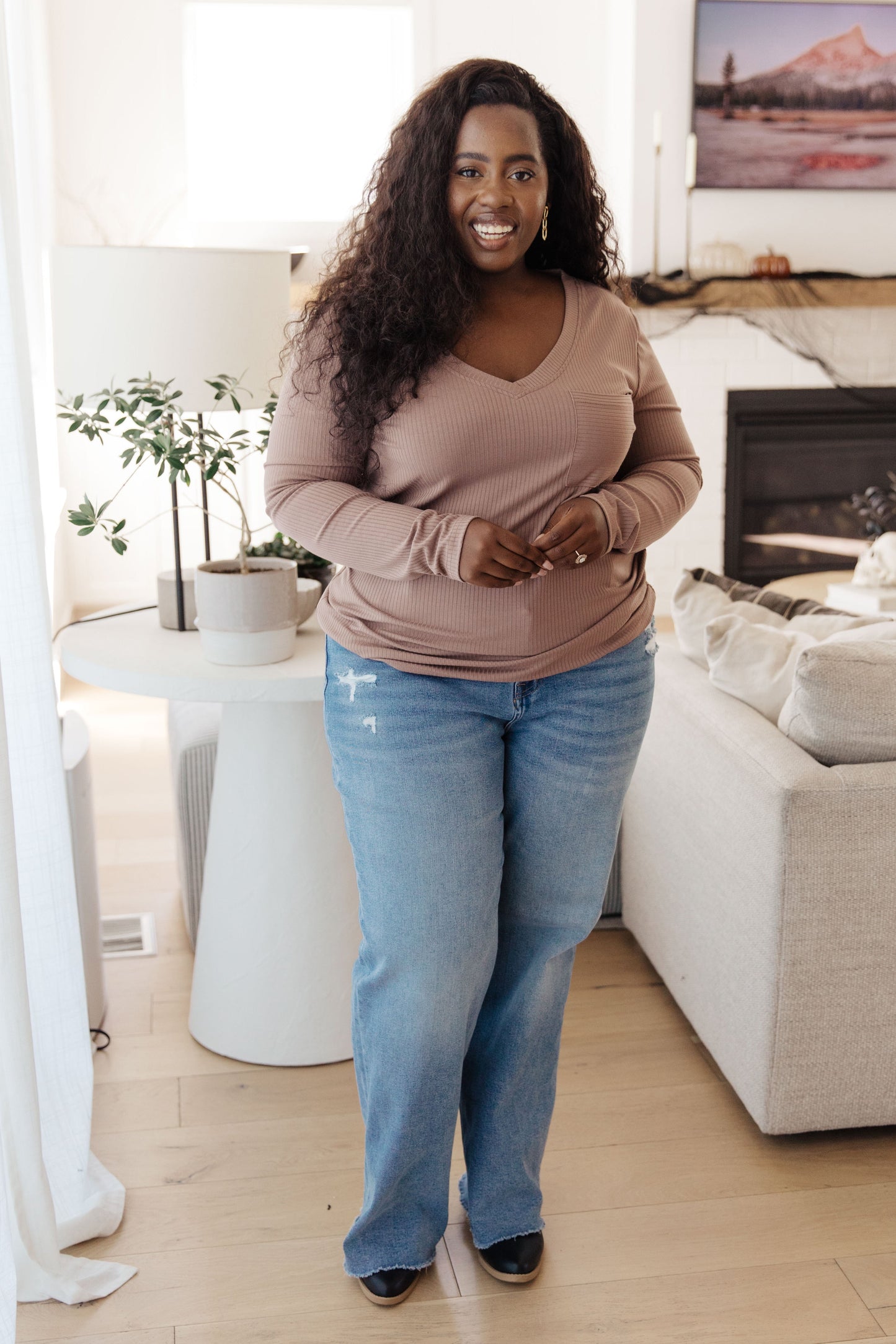 Plus size model wearing Indie Long Sleeve V-Neck Top in Beige paired with jeans.