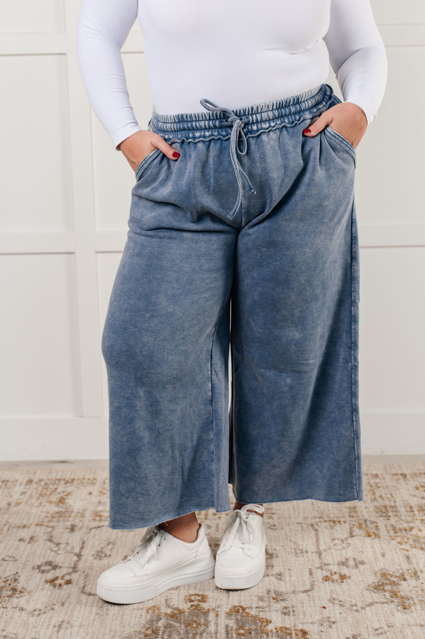 Indie Wide Leg Cropped Pants in soft fleece, featuring a trendy mineral wash in dusty blue. Designed with a drawstring elastic waist, functional side pockets, raw seam details, wide leg, and cropped length for a cozy, stylish, and relaxed look.