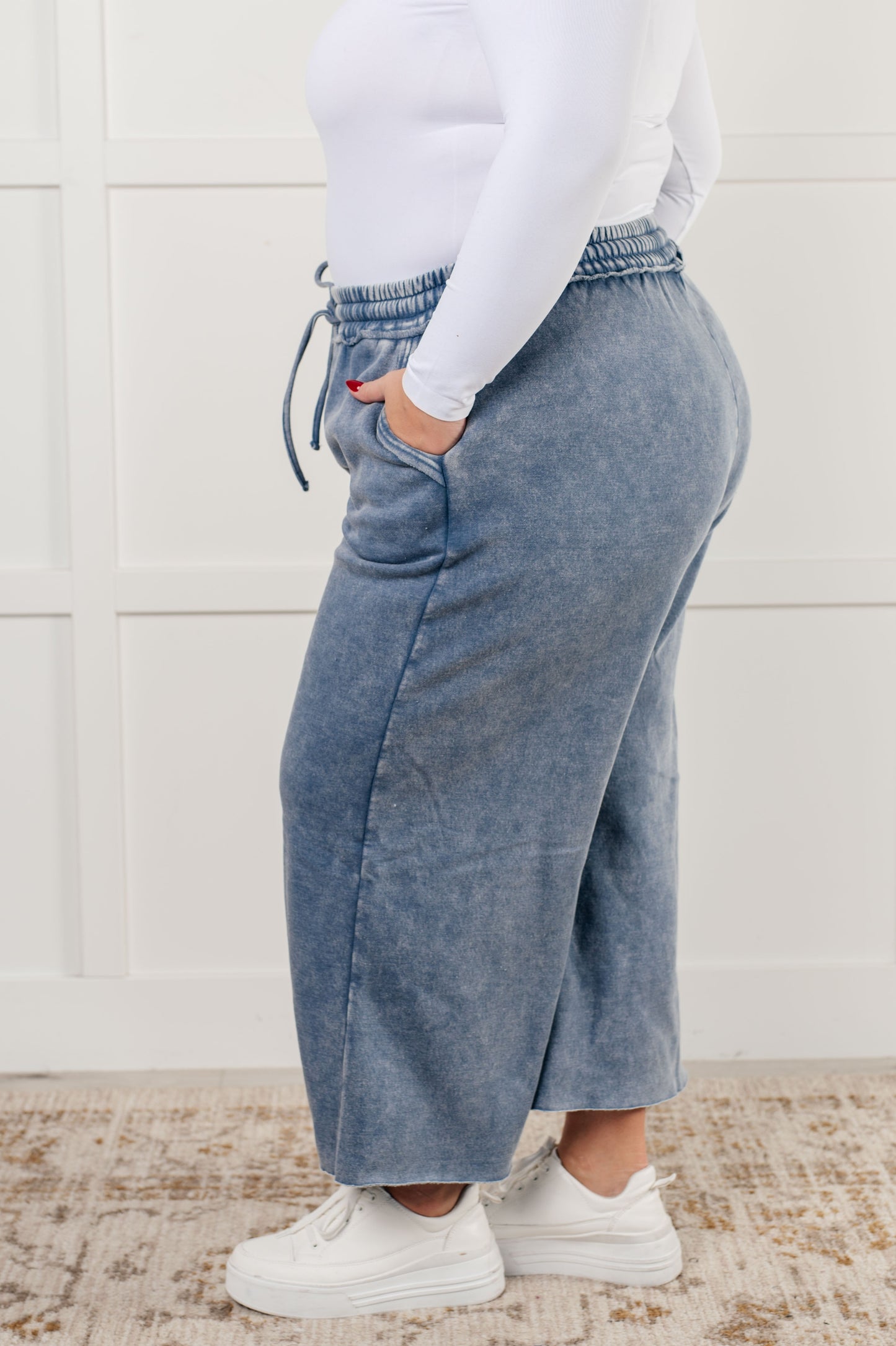 Indie Wide Leg Cropped Pants in soft fleece, featuring a trendy mineral wash in dusty blue. Designed with a drawstring elastic waist, functional side pockets, raw seam details, wide leg, and cropped length for a cozy, stylish, and relaxed look.