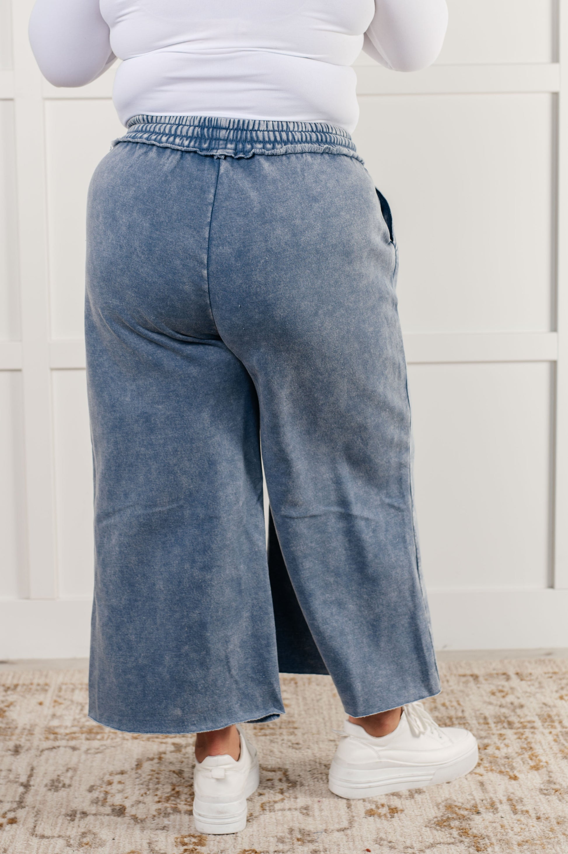 Indie Wide Leg Cropped Pants in soft fleece, featuring a trendy mineral wash in dusty blue. Designed with a drawstring elastic waist, functional side pockets, raw seam details, wide leg, and cropped length for a cozy, stylish, and relaxed look.