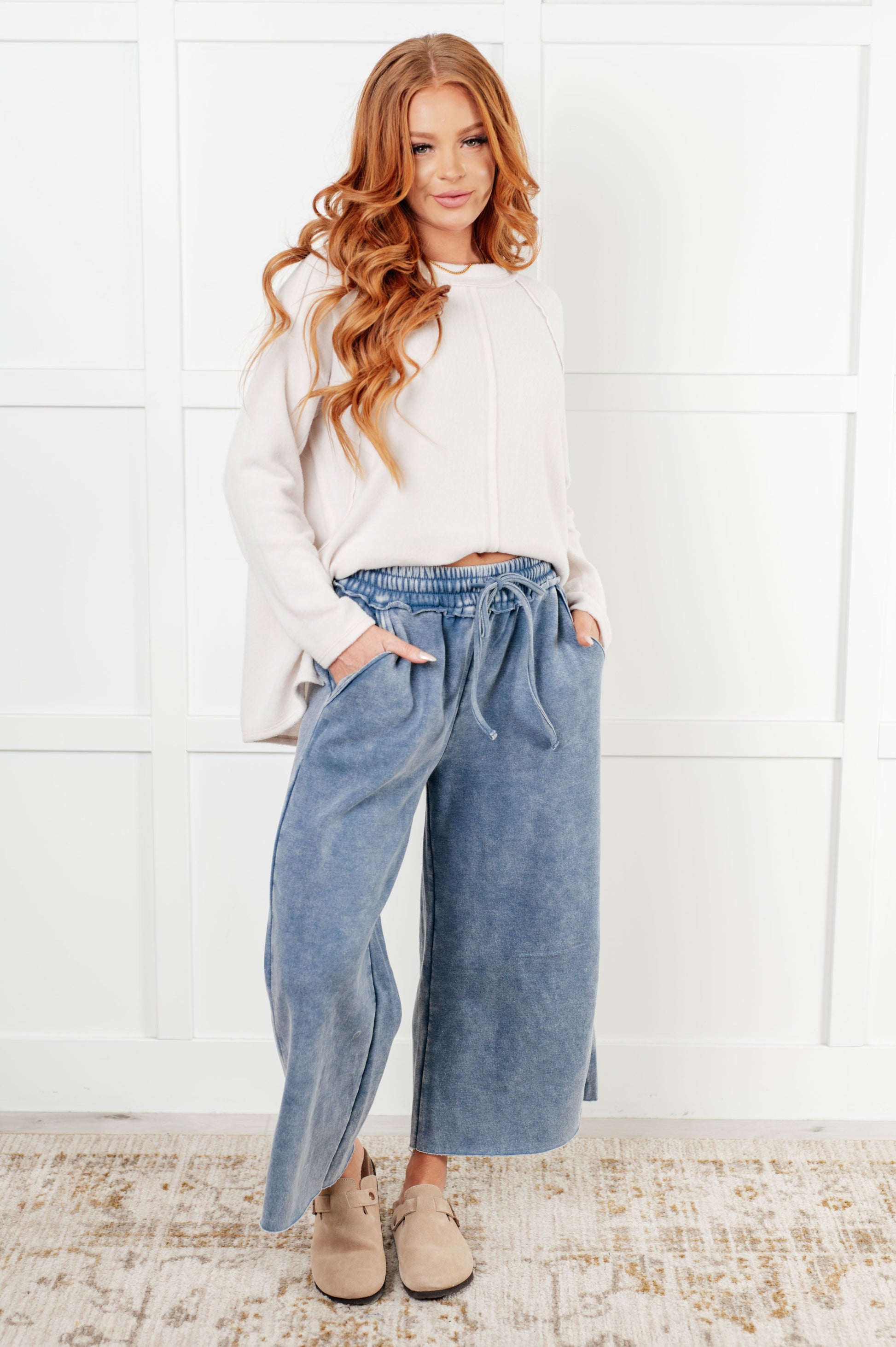 Indie Wide Leg Cropped Pants in soft fleece, featuring a trendy mineral wash in dusty blue. Designed with a drawstring elastic waist, functional side pockets, raw seam details, wide leg, and cropped length for a cozy, stylish, and relaxed look.