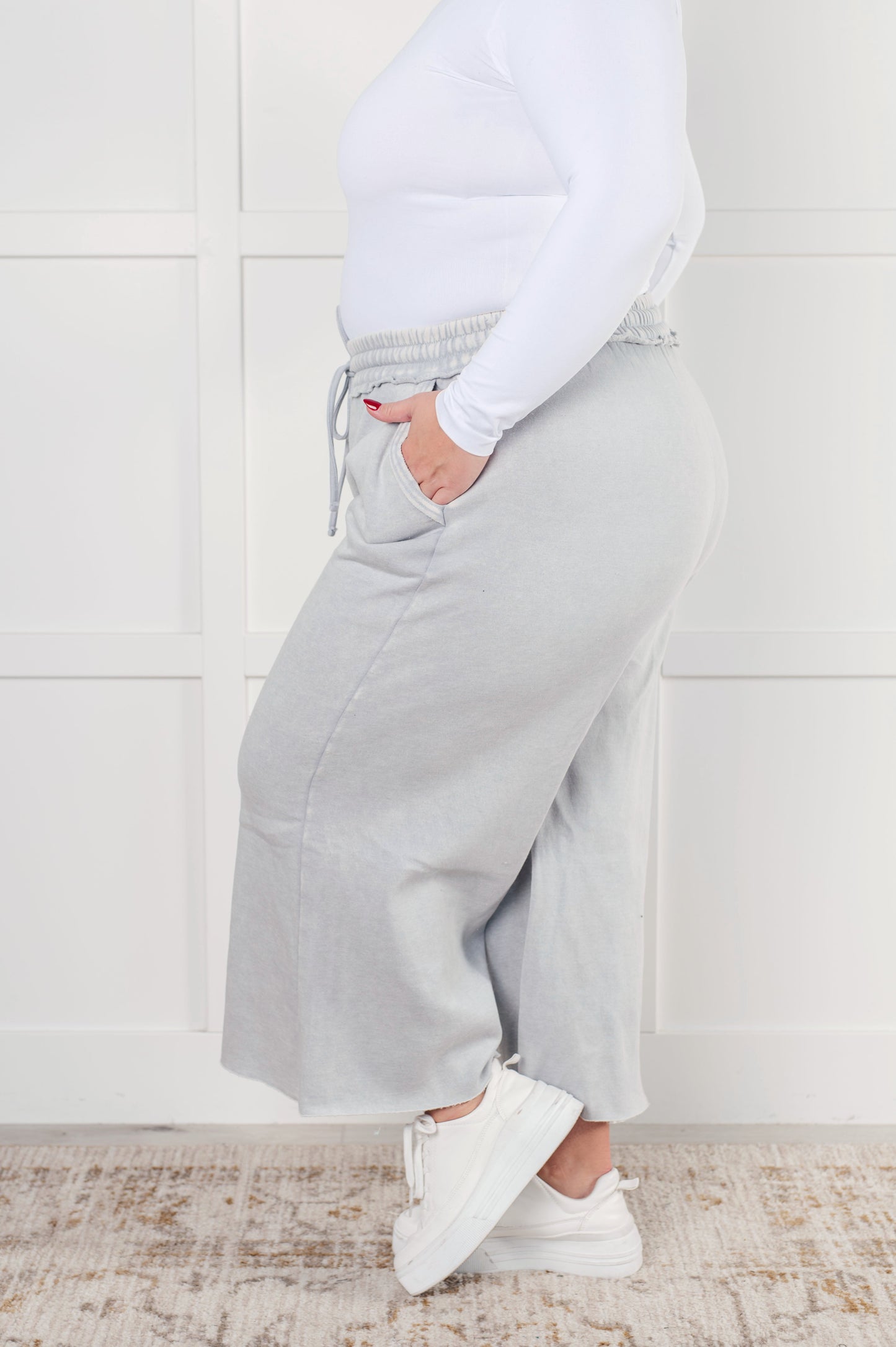 Indie Wide Leg Cropped Pants in soft fleece, featuring a trendy mineral wash in light gray. Designed with a drawstring elastic waist, functional side pockets, raw seam details, wide leg, and cropped length for a cozy, stylish, and relaxed look.