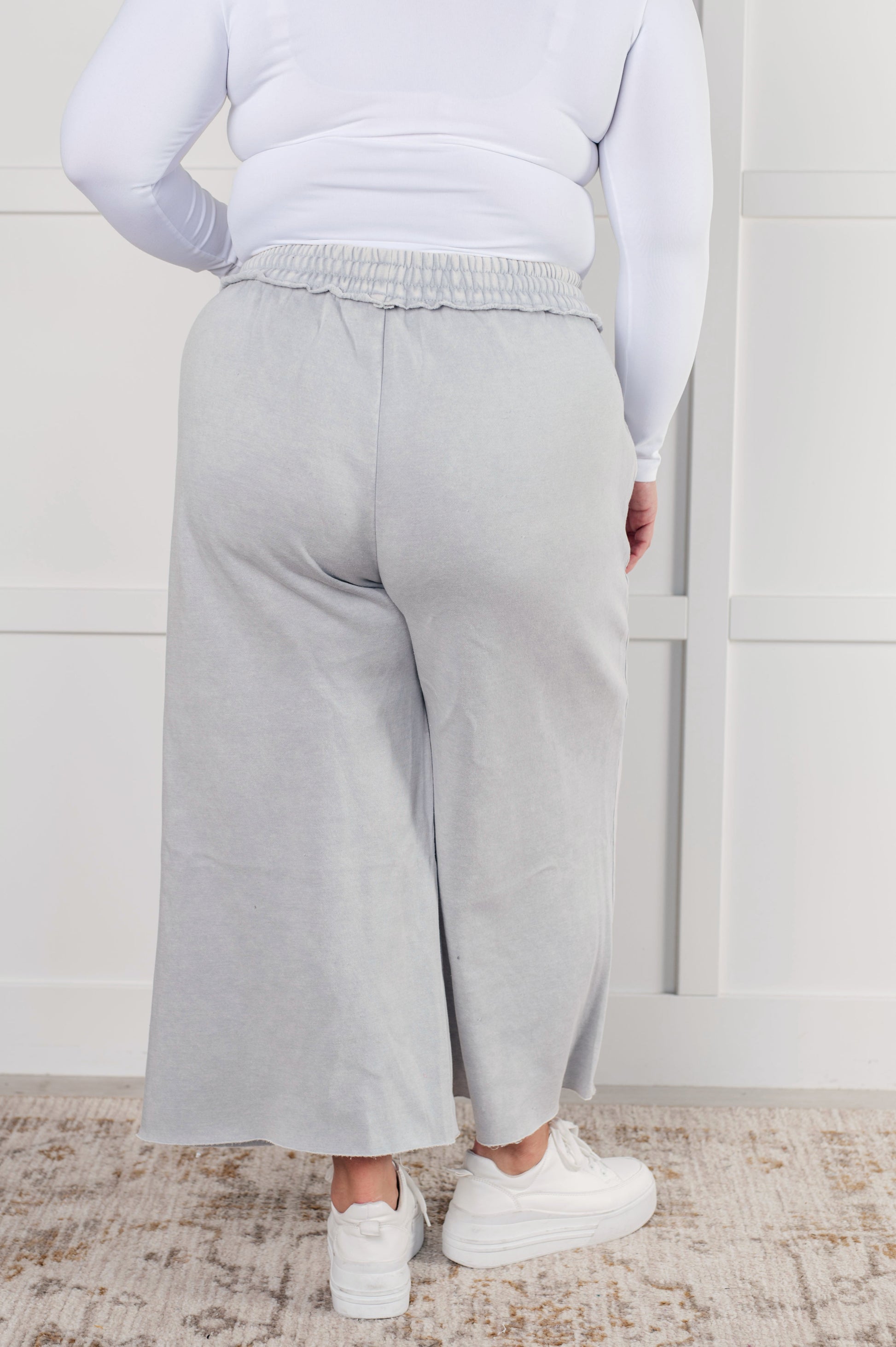 Indie Wide Leg Cropped Pants in soft fleece, featuring a trendy mineral wash in light gray. Designed with a drawstring elastic waist, functional side pockets, raw seam details, wide leg, and cropped length for a cozy, stylish, and relaxed look.