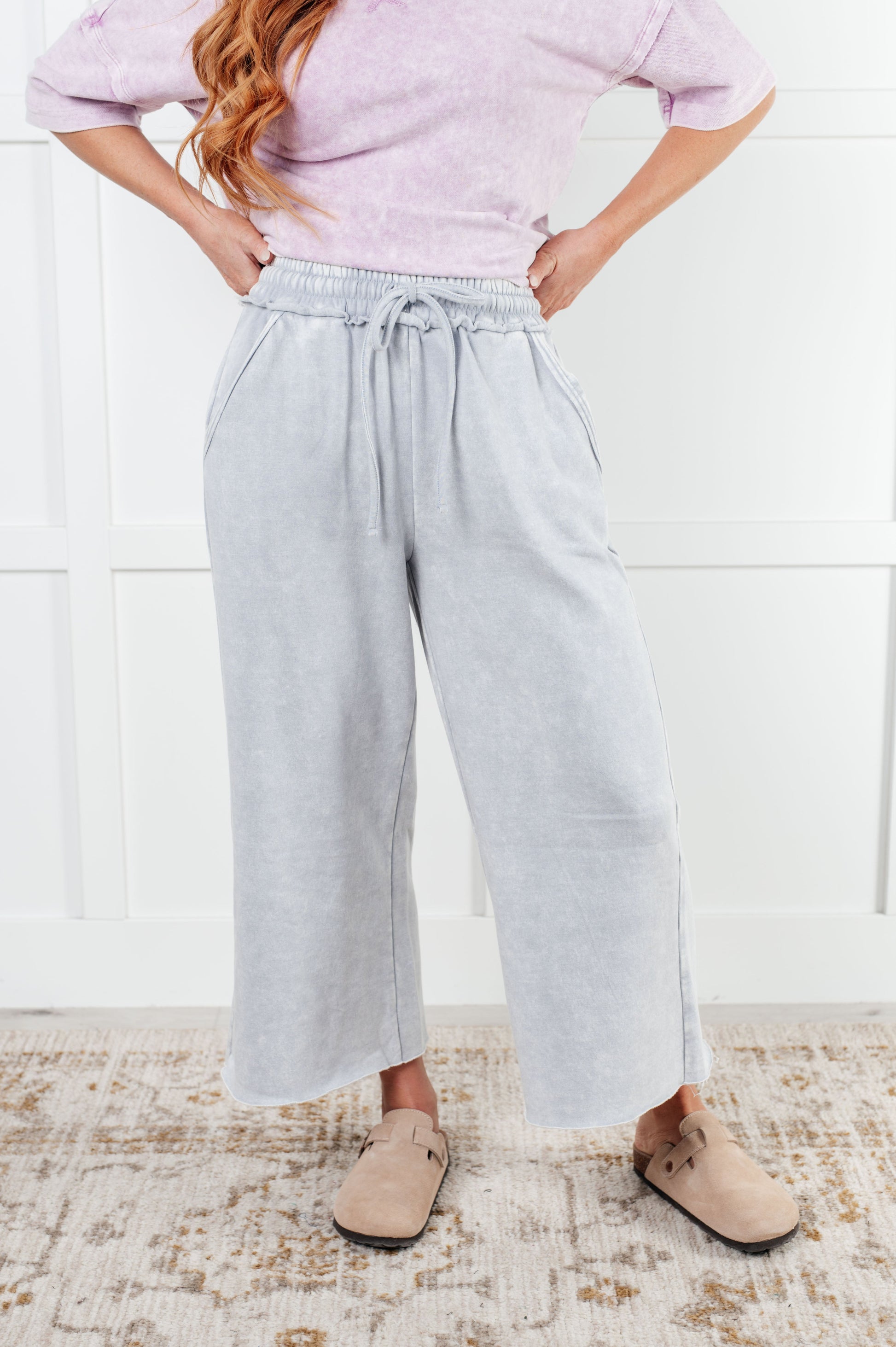 Indie Wide Leg Cropped Pants in soft fleece, featuring a trendy mineral wash in light gray. Designed with a drawstring elastic waist, functional side pockets, raw seam details, wide leg, and cropped length for a cozy, stylish, and relaxed look.