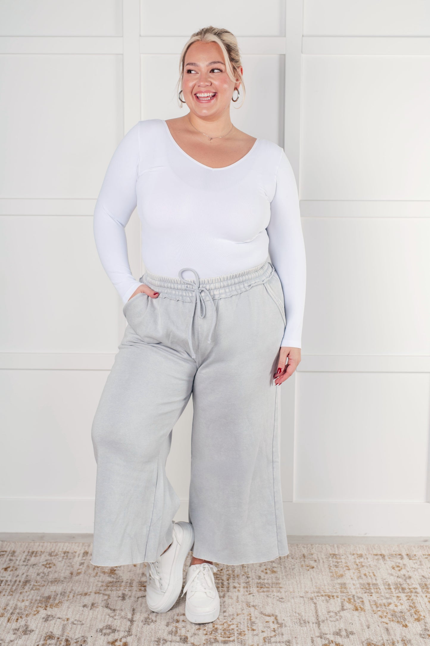 Indie Wide Leg Cropped Pants in soft fleece, featuring a trendy mineral wash in light gray. Designed with a drawstring elastic waist, functional side pockets, raw seam details, wide leg, and cropped length for a cozy, stylish, and relaxed look.