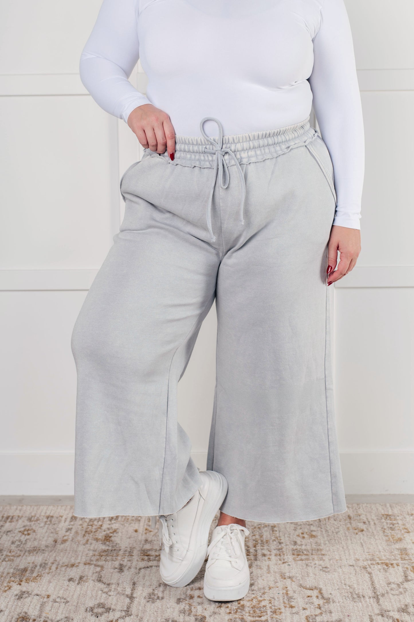 Indie Wide Leg Cropped Pants in soft fleece, featuring a trendy mineral wash in light gray. Designed with a drawstring elastic waist, functional side pockets, raw seam details, wide leg, and cropped length for a cozy, stylish, and relaxed look.