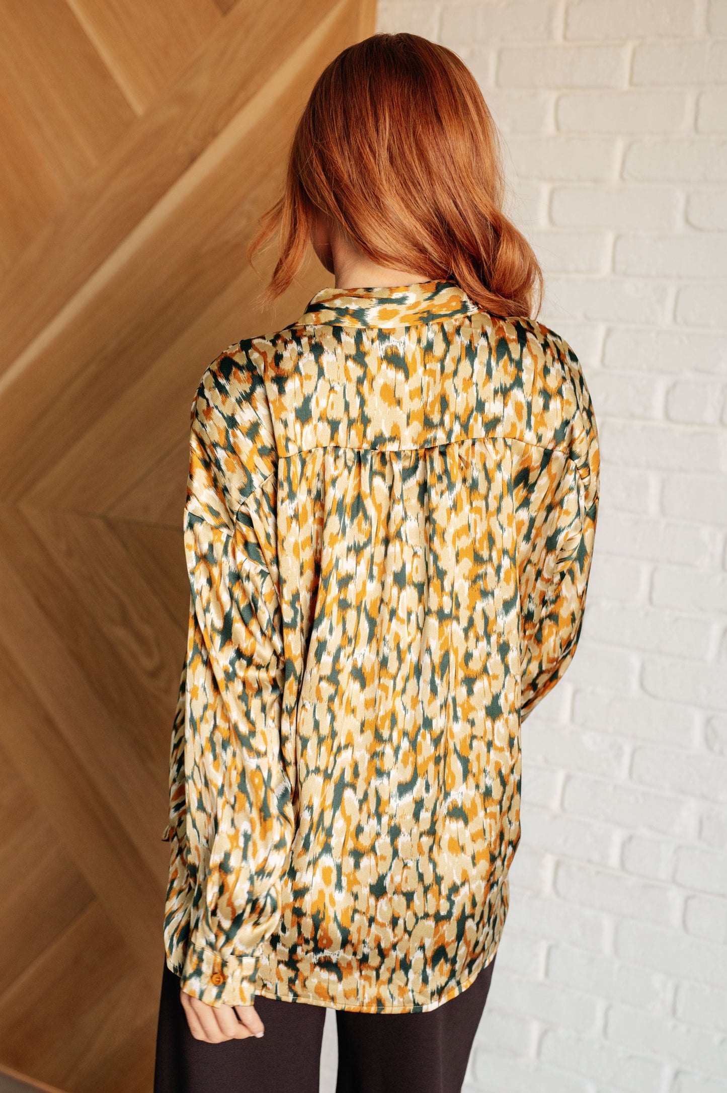 Mustard and tan abstract print blouse made from poly satin, featuring a collared neckline, button front fastening, and buttoned sleeve cuffs.