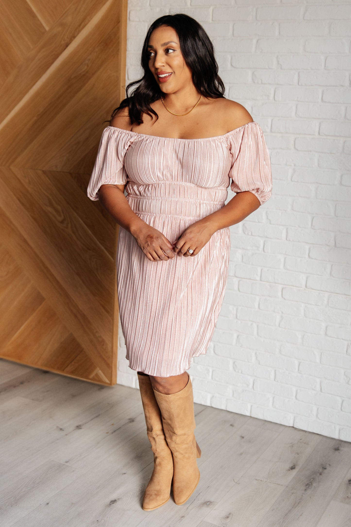 Pink poly satin plissé dress with a scoop neckline, off-shoulder option, short balloon sleeves, elastic cuffs, and a lined skirt.