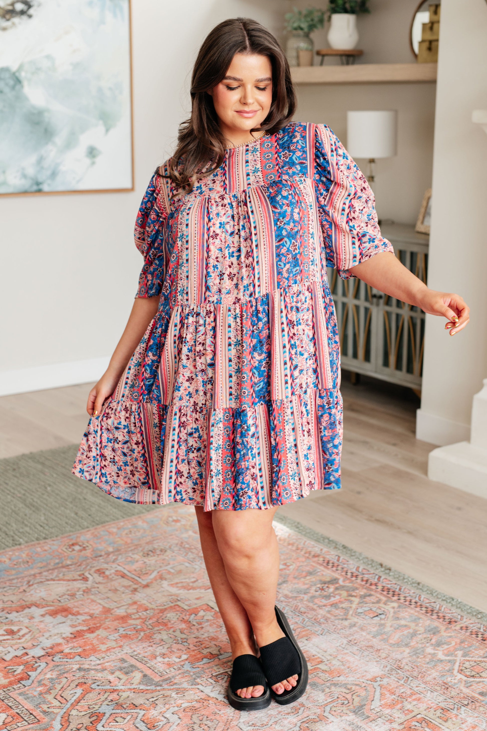 Plus-size model wearing Rylee Tiered Dress in pink-and-blue floral print with sandals, full body view.
