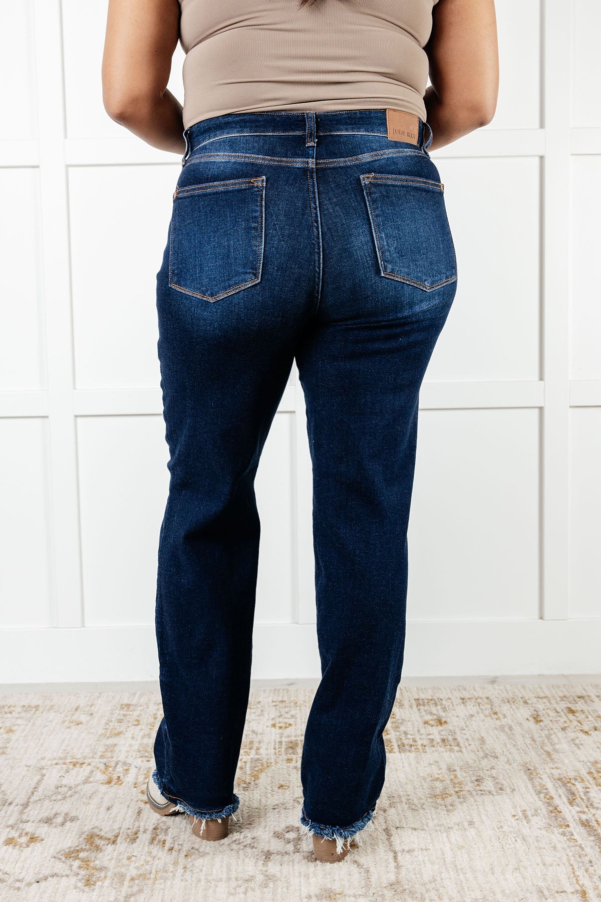 Back view of plus size Mid Rise Jean with dark wash, non-distressed design, straight-leg silhouette, and frayed hem.