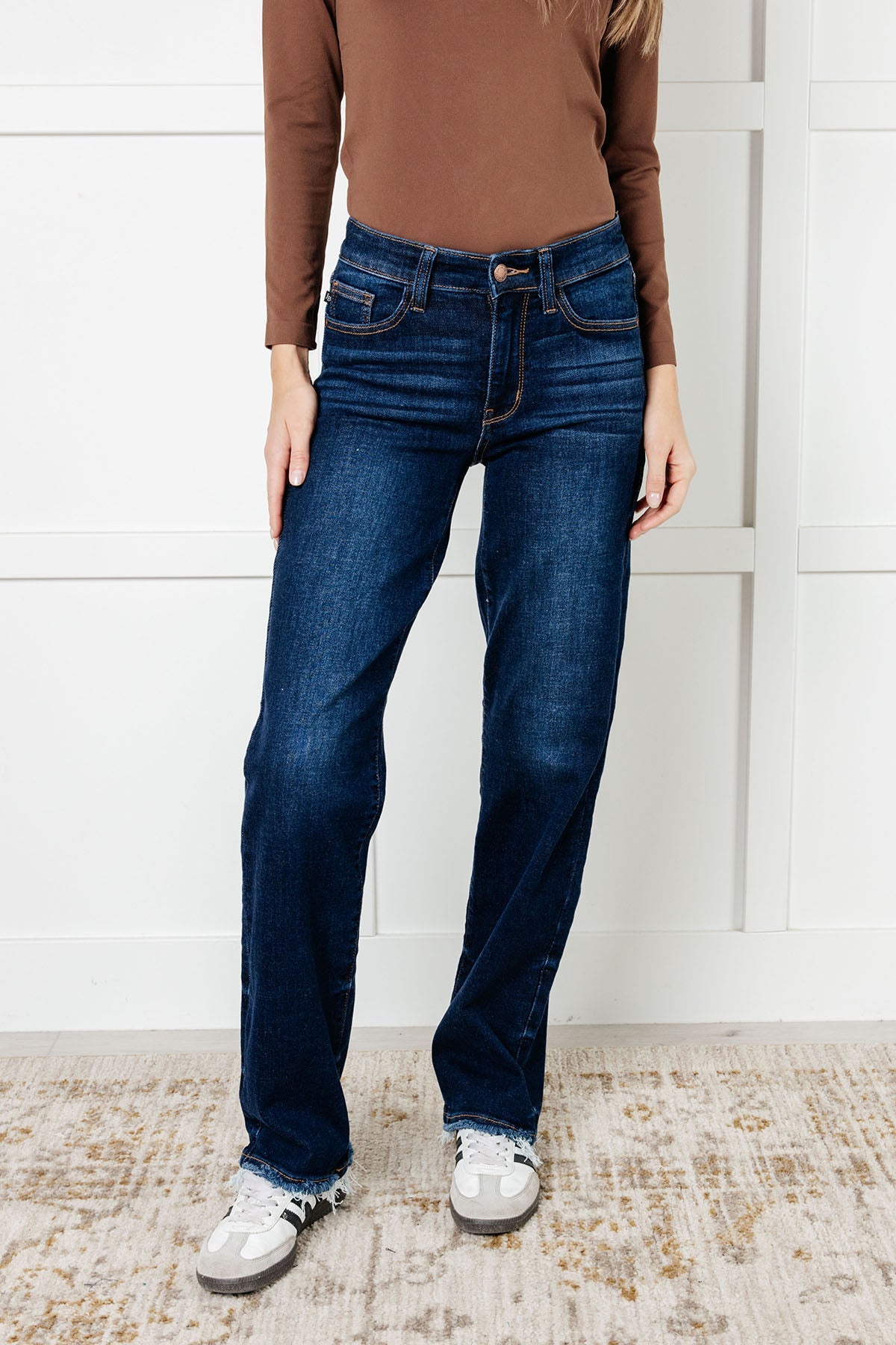  Mid Rise Jean with dark wash, non-distressed design, straight-leg silhouette, and frayed hem.