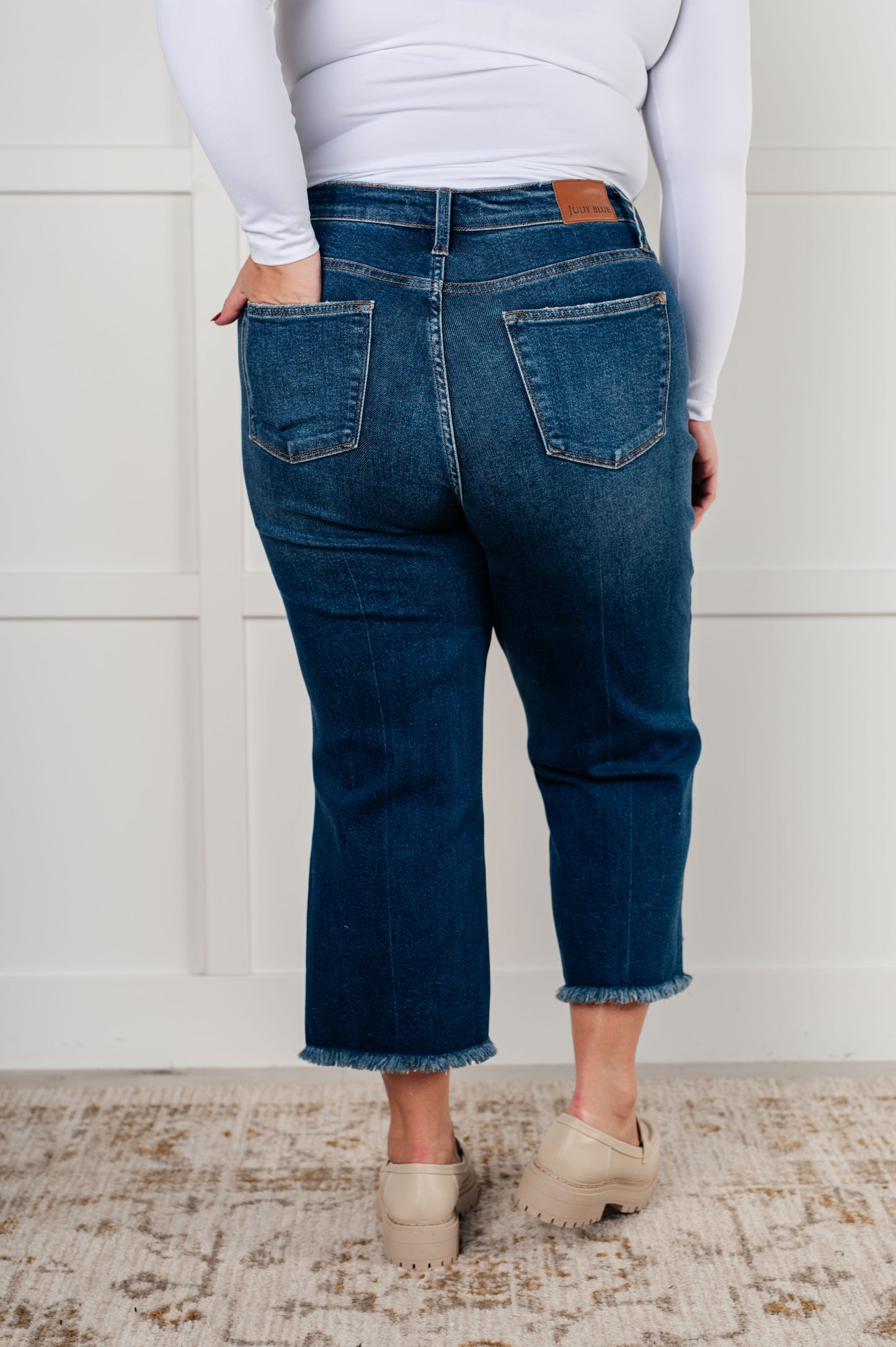 Plus size back view of the Janice High Rise Button Fly Wide Leg Crop Jeans by Judy Blue in a dark wash. Features a high-rise waist, button fly closure, wide leg crop silhouette, raw hem, and 4-way stretch for comfort and style. Perfect for a playful yet sophisticated look.