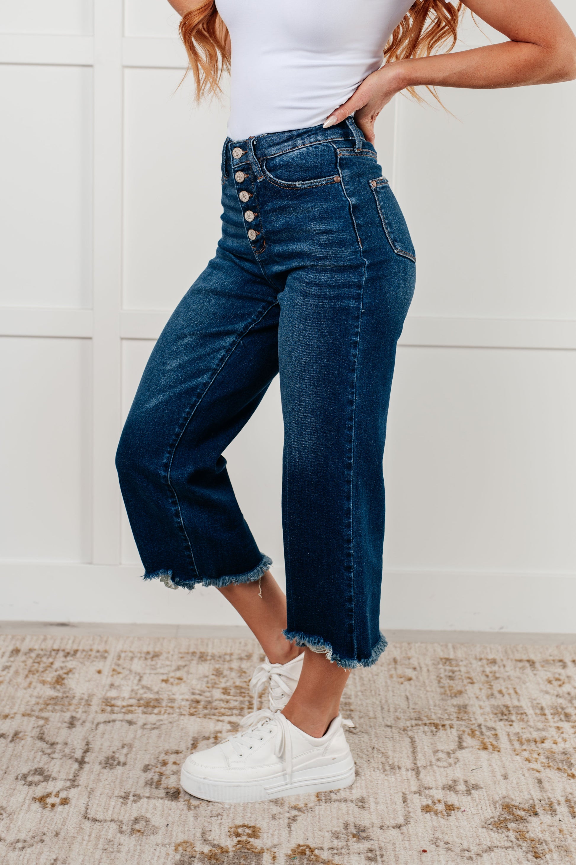 Side view of the Janice High Rise Button Fly Wide Leg Crop Jeans by Judy Blue in a dark wash. Features a high-rise waist, button fly closure, wide leg crop silhouette, raw hem, and 4-way stretch for comfort and style. Perfect for a playful yet sophisticated look.