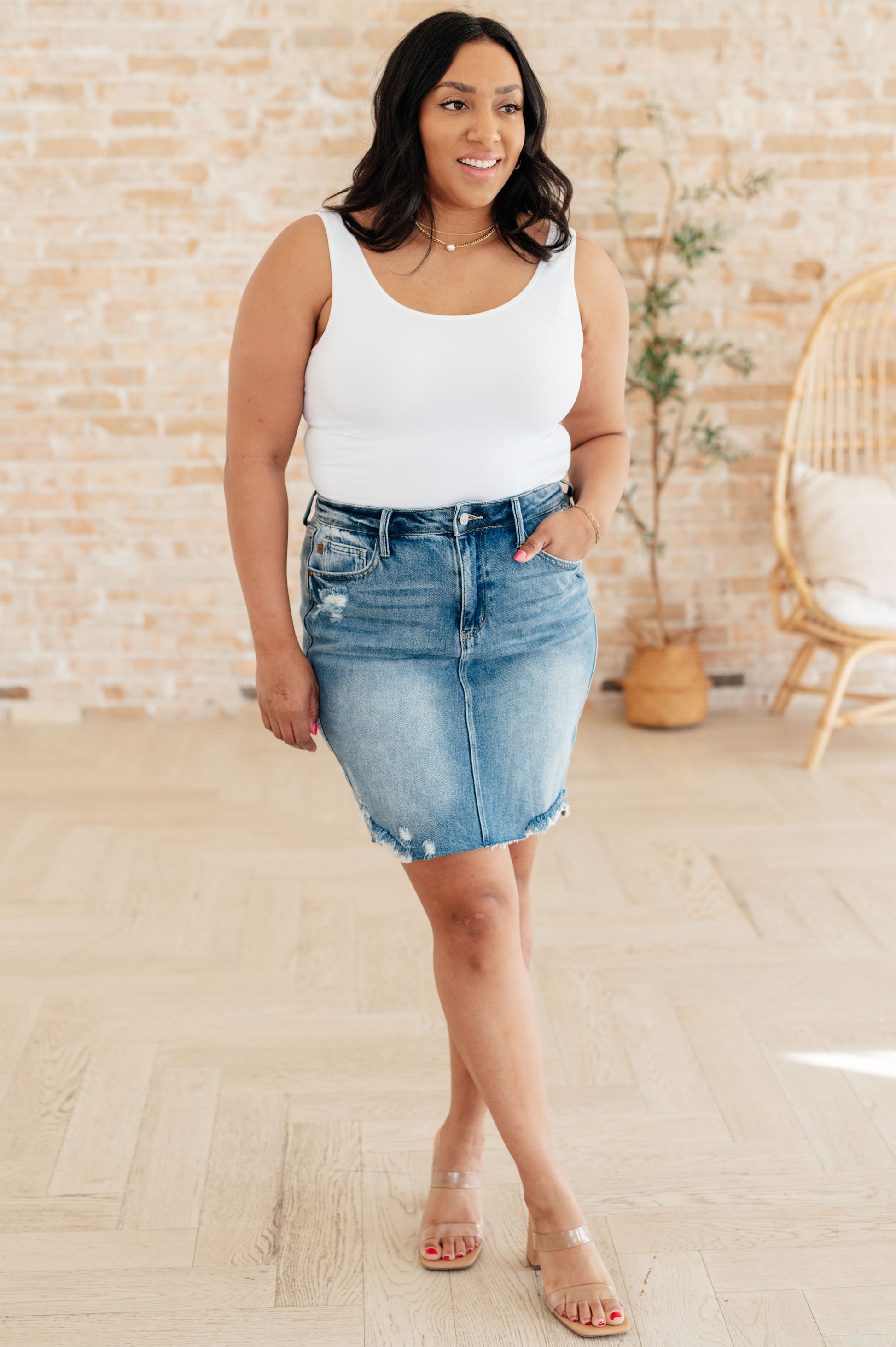 High-rise denim skirt with distressed details and raw hem. Light blue wash, zip fly closure, and a rigid front panel with a stretchy back panel for comfort.