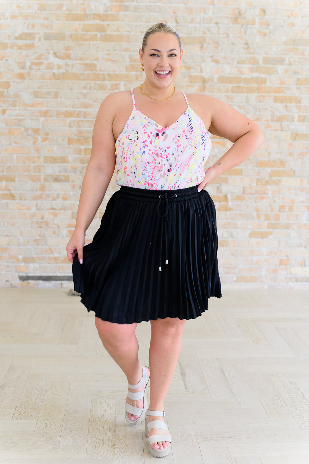 Full body view of Scarlett Pink Watercolor Printed Cami paired with a pleated skirt and sandals.