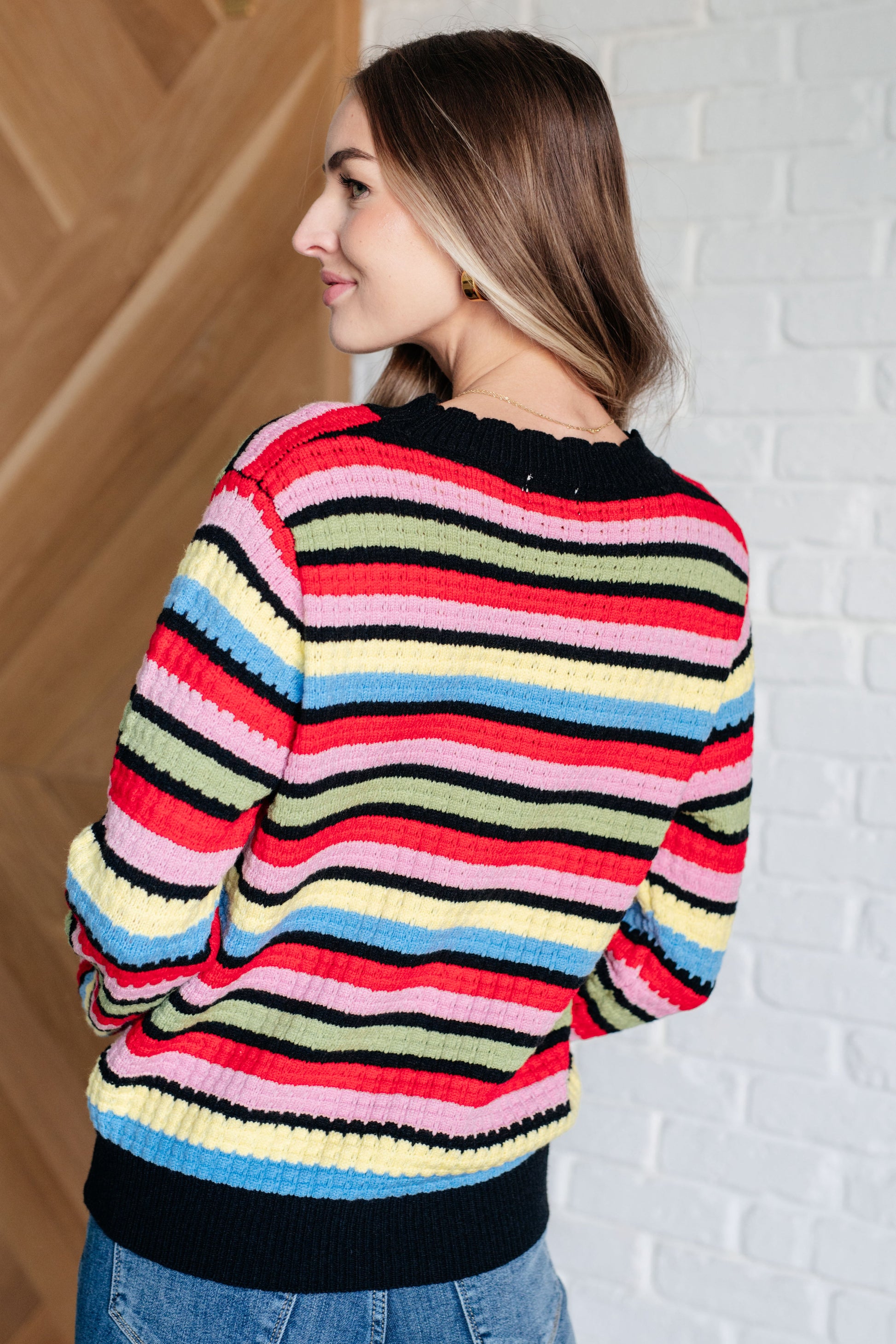 A women's striped sweater made of textured mid-weight knit fabric, featuring a crew neckline, long sleeves, and a comfortable fit. stripes of red, pink, blue, green, black, and yellow.